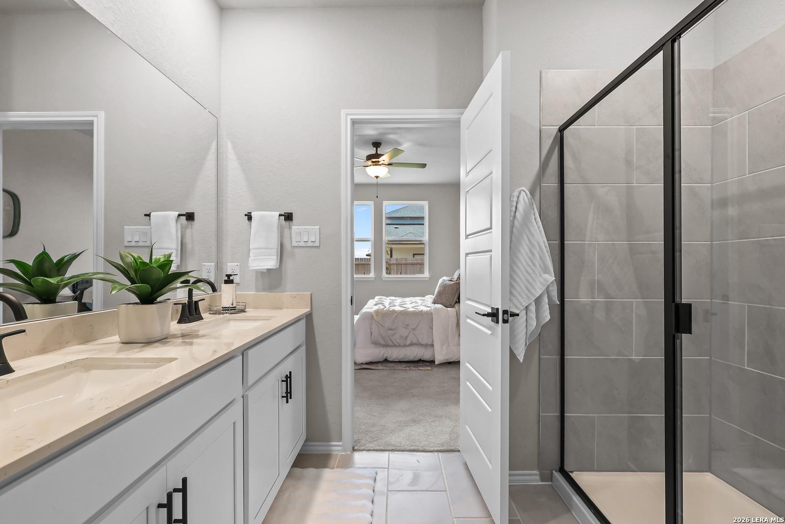 Modern bathroom with double vanity and walk-in glass shower in The Daphne H floor plan, Hannah Heights, Seguin, Texas.