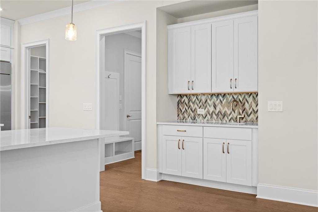 Modern white kitchen with herringbone glass tile backsplash, island, and cabinets in Davidson Homes The Arlington A, East Cobb