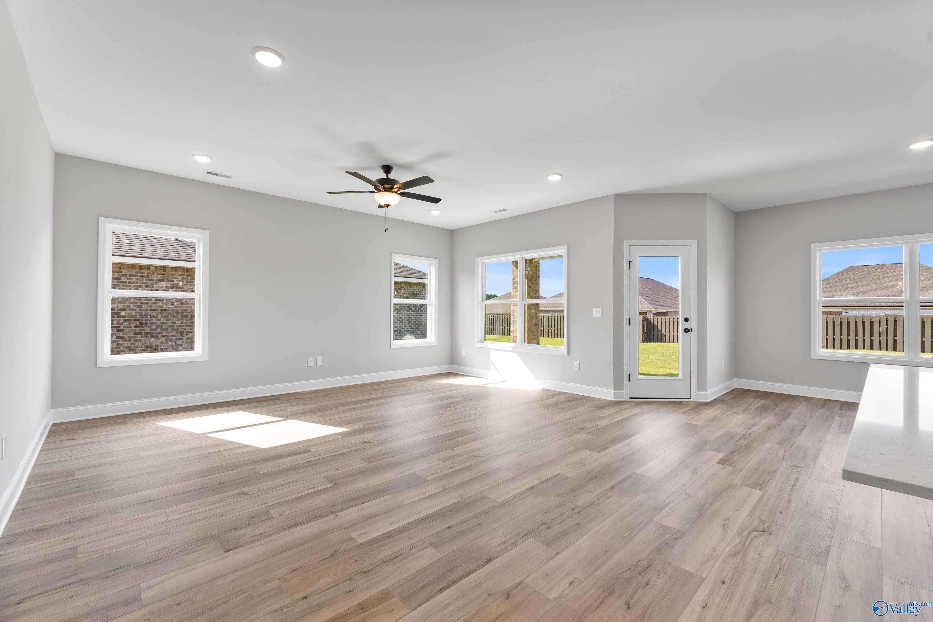 Bright living room with light wood floors, large windows to backyard, ceiling fan in Davidson Homes The Franklin B, Hazel Green AL