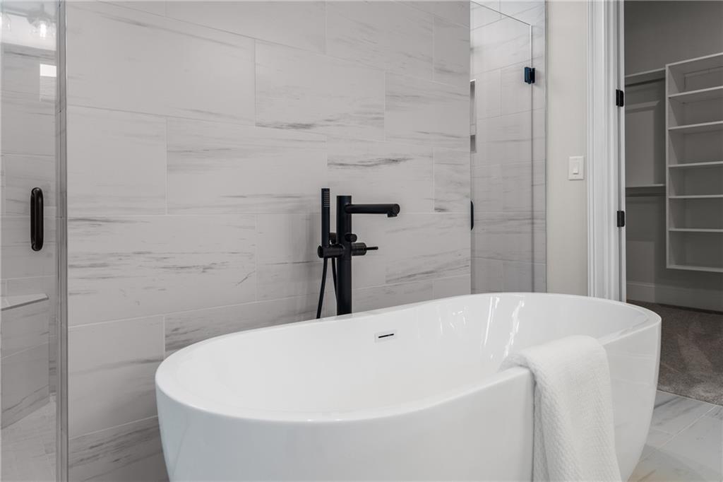Luxurious master bathroom featuring freestanding soaking tub, black faucet, and frameless glass shower in Davidson Homes Seaside B, Woodstock, Georgia