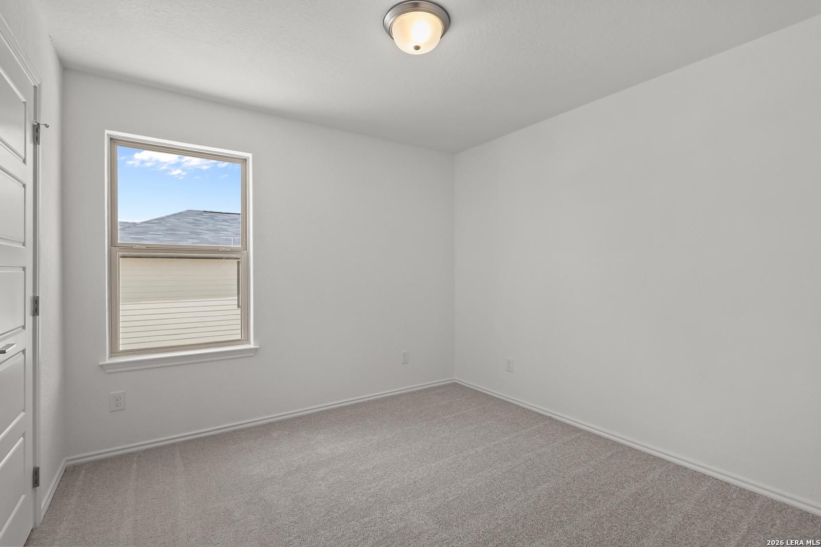 Bright, carpeted bedroom with neutral walls in The Gillian C floor plan by Davidson Homes in San Antonio, Texas.