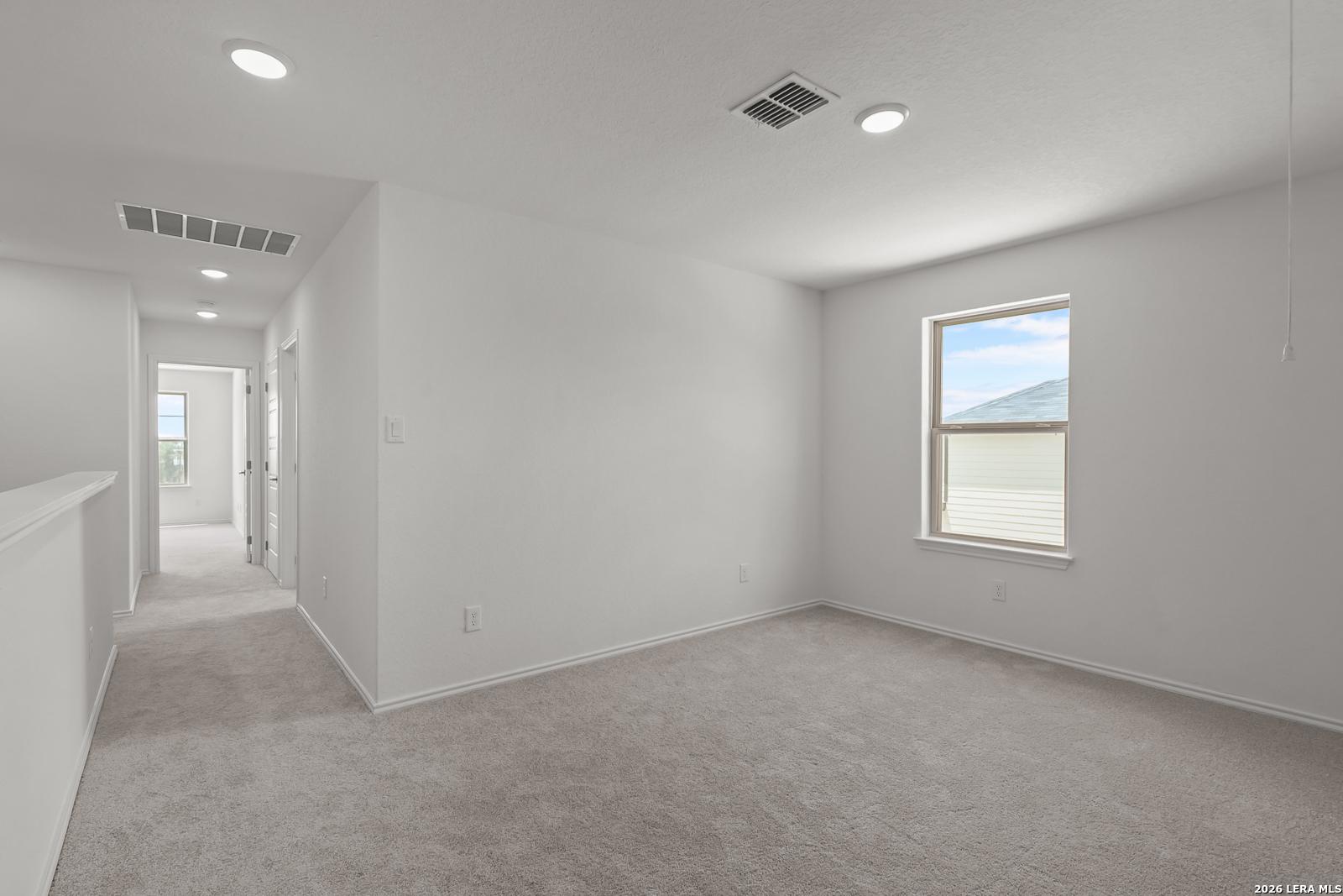 Bright carpeted bedroom with recessed lighting in The Gillian C floor plan by Davidson Homes in San Antonio, Texas.