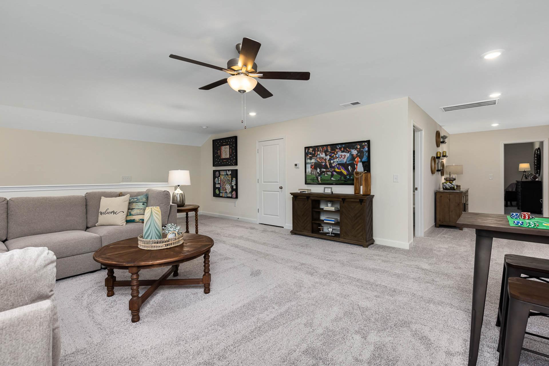 Spacious living room at Weatherford East in Angier NC with beige sofa gray carpet wall TV bar counter and ceiling fan