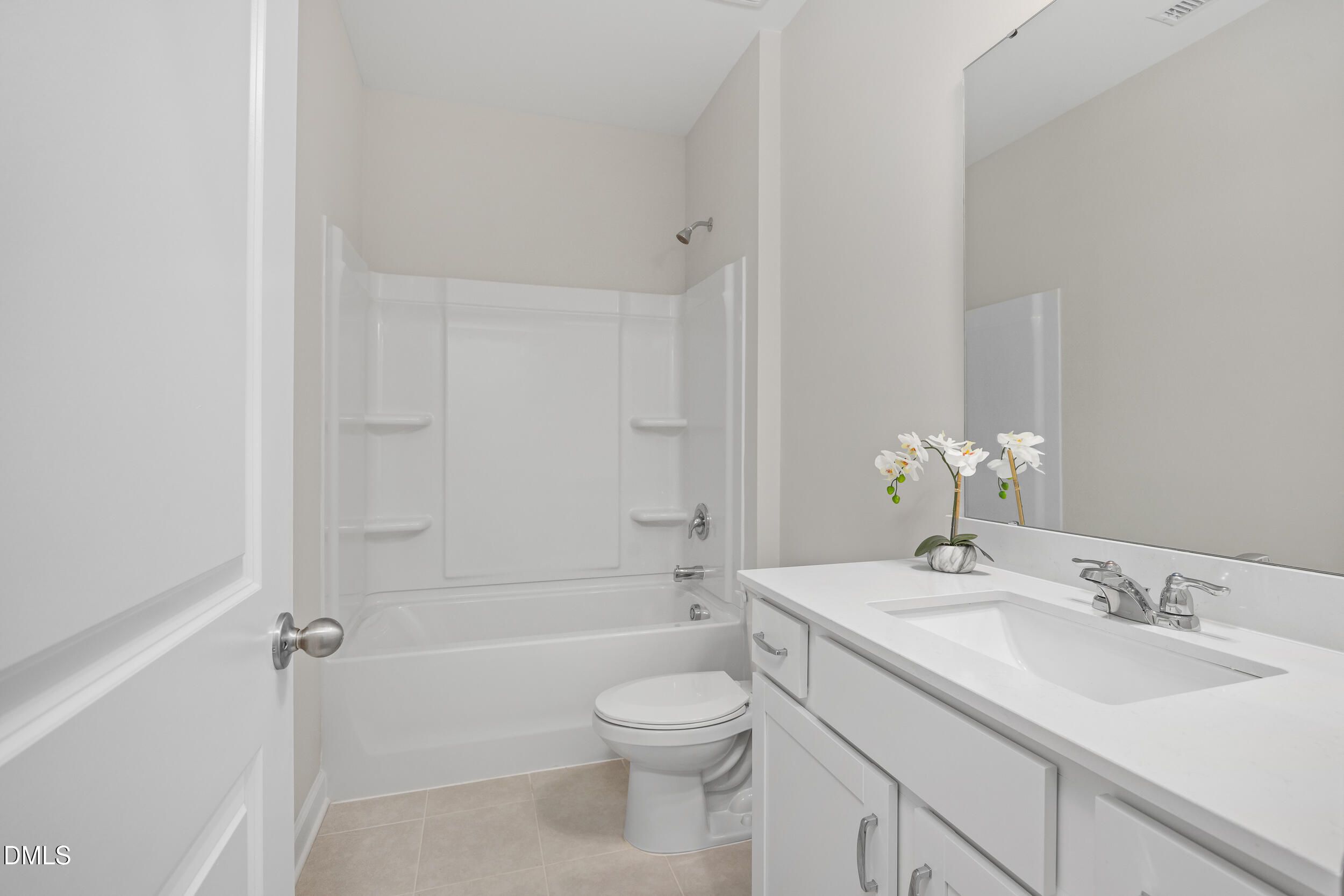Modern guest bathroom featuring white tub, shower, vanity sink, and orchids in Davidson Homes The Preston C, Lillington, NC