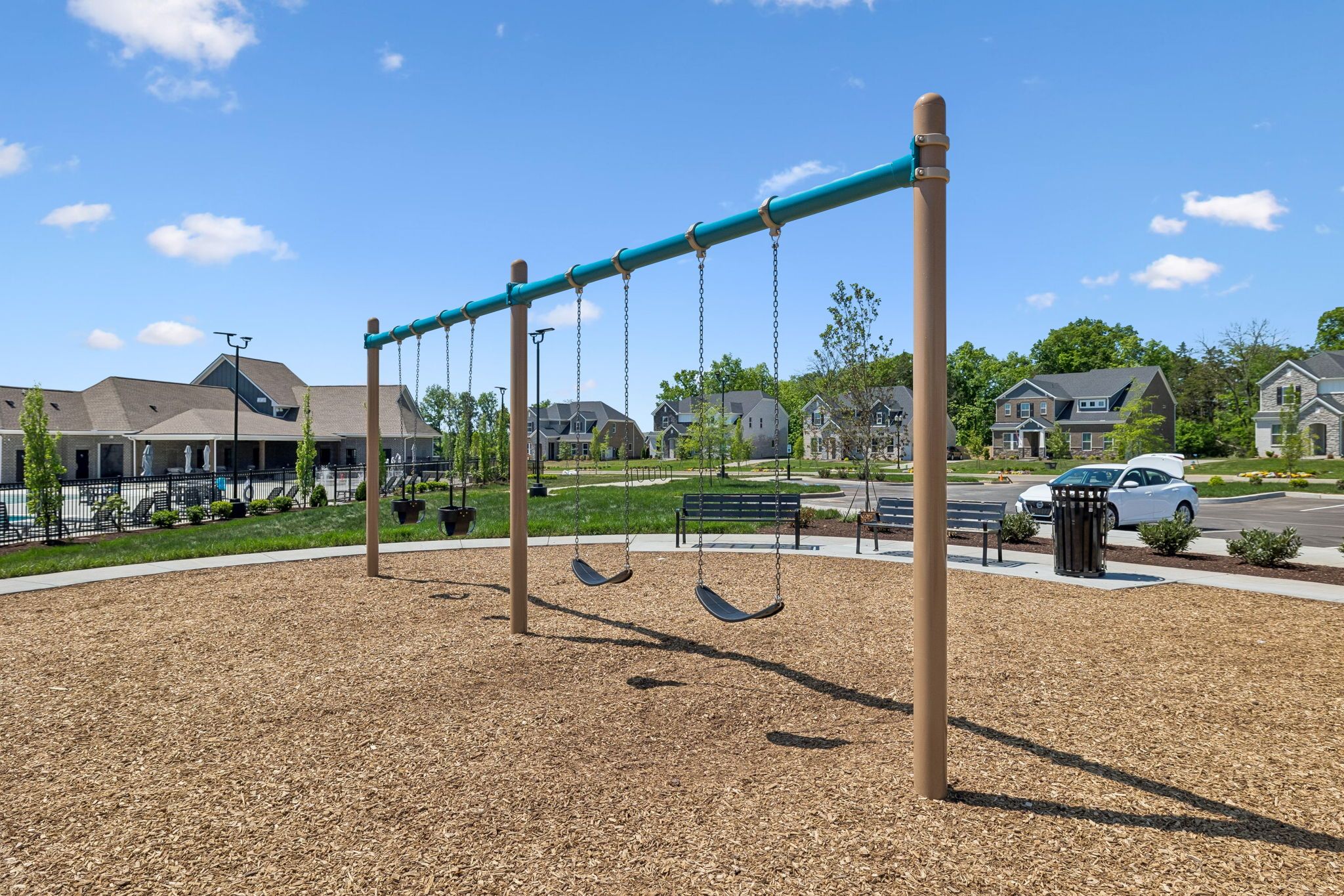 Playground swings at Bradshaw Farms in Mt. Juliet, Tennessee, featuring a mulched play area and neighborhood views.