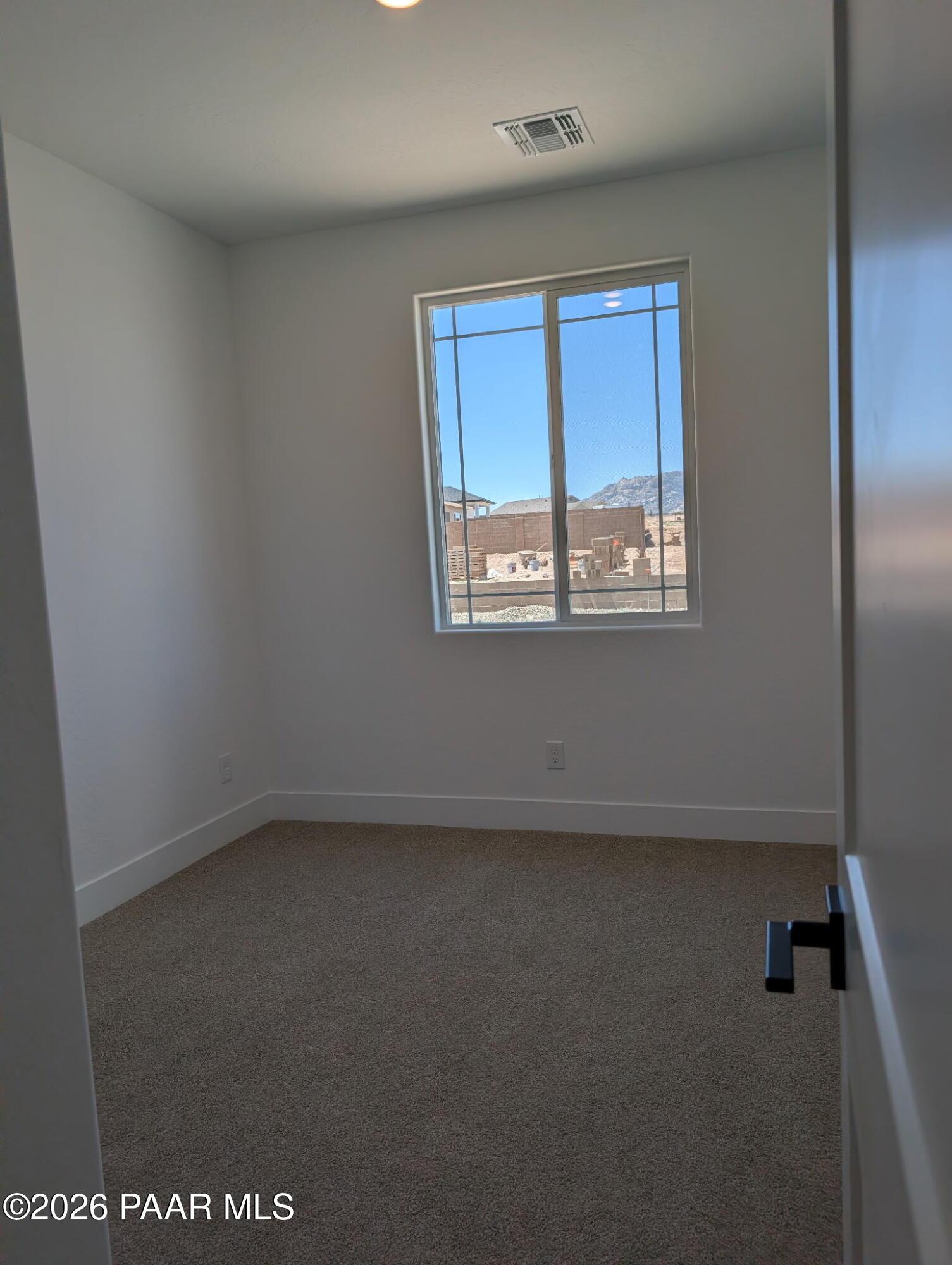 Bright bedroom with neutral carpet and window view in The Frontier II F home at South Ranch, Prescott, Arizona.