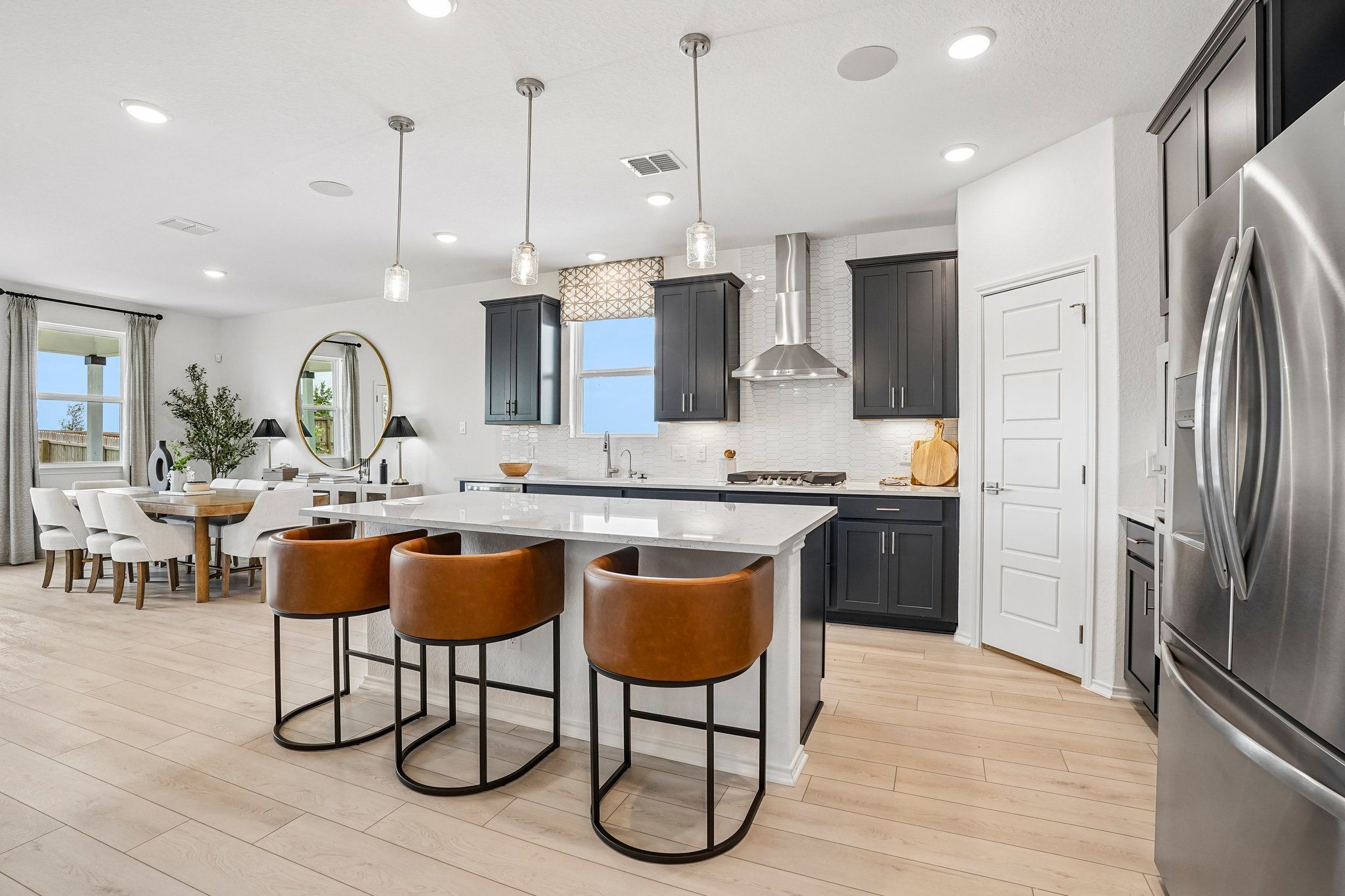 Modern kitchen with dark cabinets, quartz island, and leather bar stools at Morgan Meadows in San Antonio, Texas.