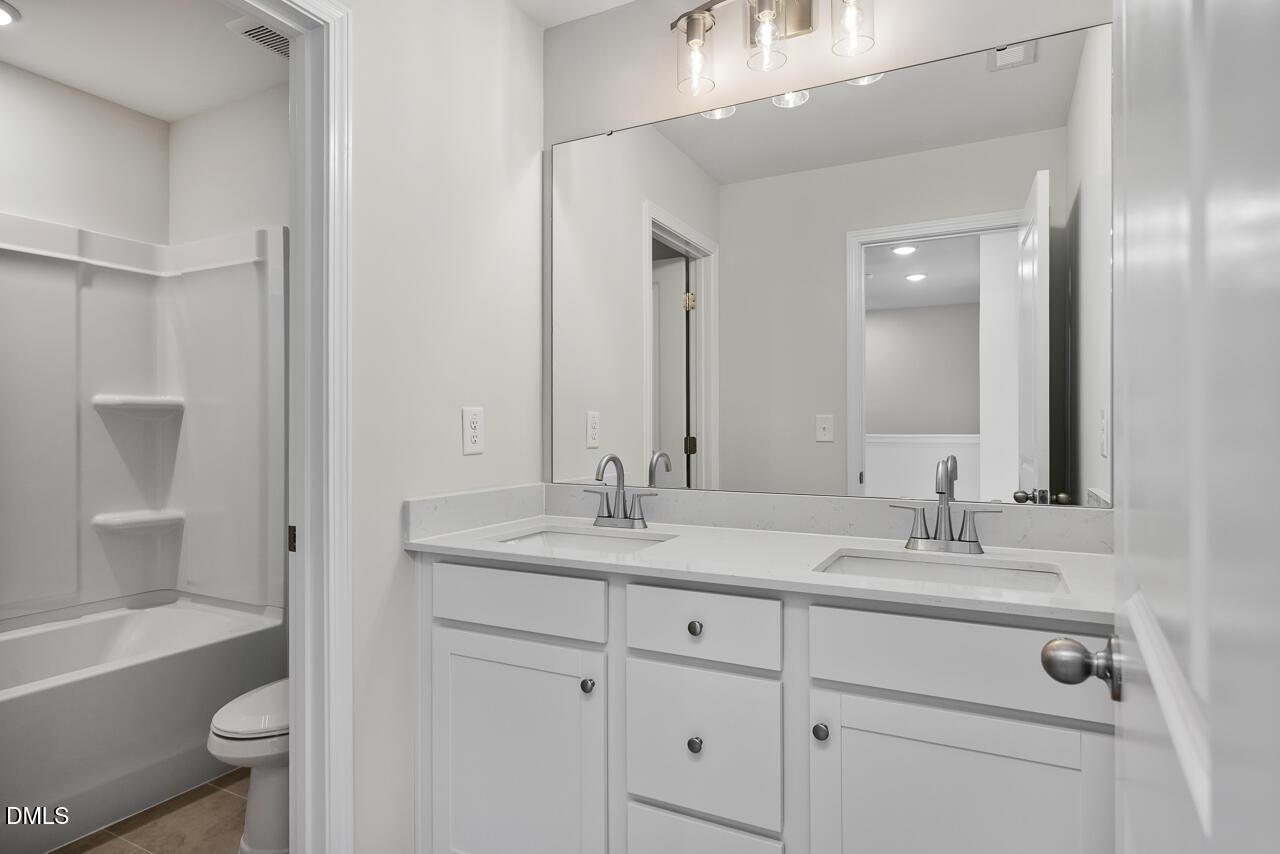 Modern bathroom with dual-sink vanity and shower-tub combo in The Mitchell Interior by Davidson Homes, Knightdale, NC.