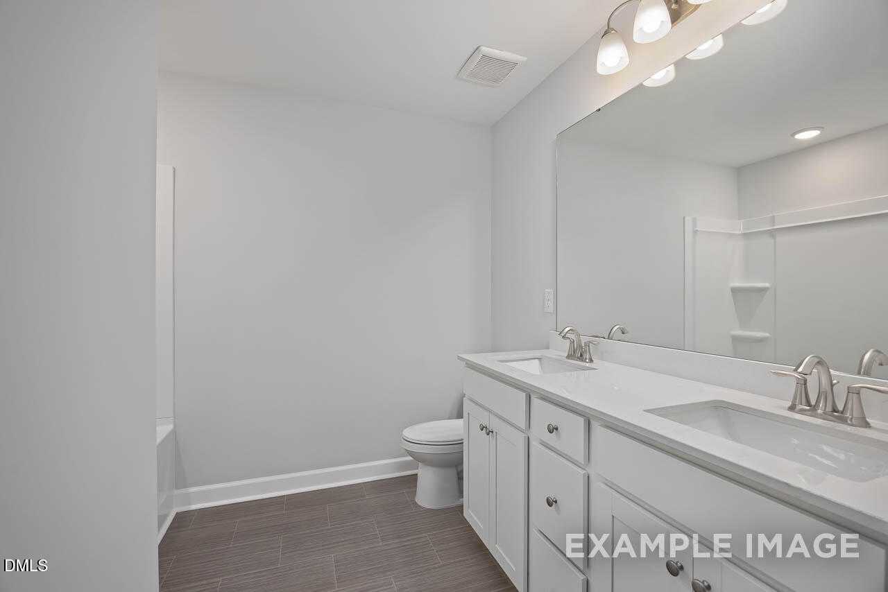 Modern double-sink vanity with white cabinets and large mirror in 2.5-bath The Warren Interior, Davidson Homes, Fuquay-Varina, NC