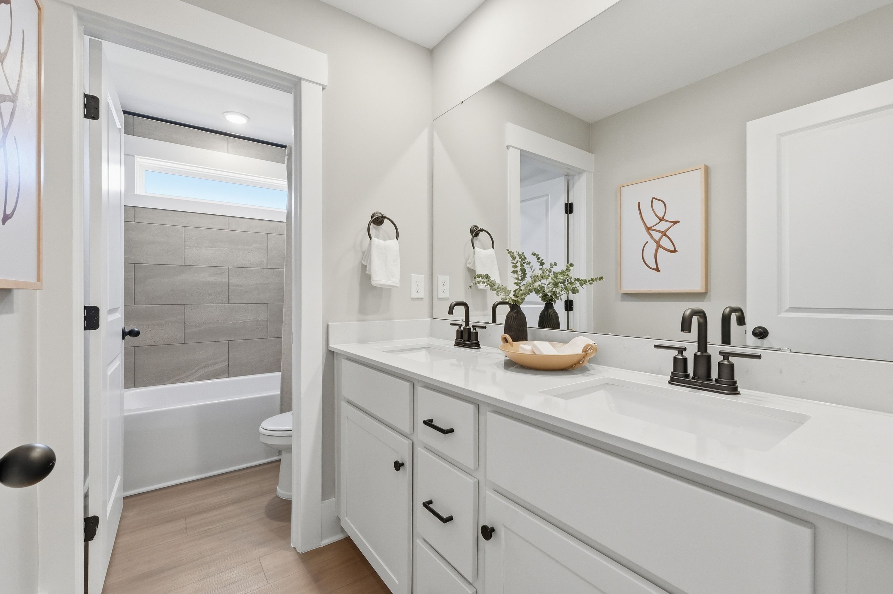 Spacious modern bathroom in Berry Cove, New Market Alabama with double vanity, subway tile tub surround, hardwood floors