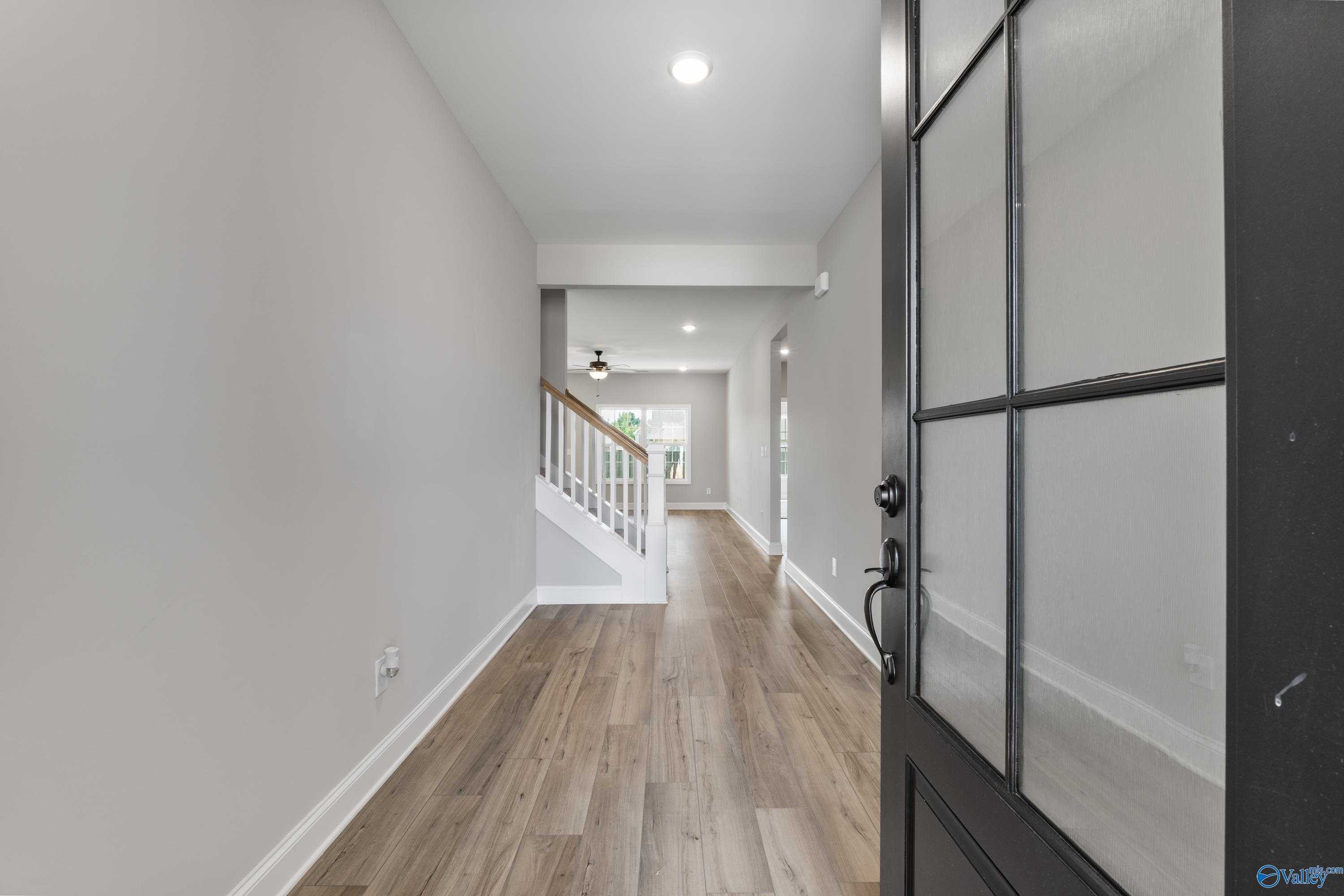 Bright entry hallway with light gray walls, hardwood floors, and staircase in 4-bedroom Davidson Homes The Montgomery B With Bonus, Toney, AL
