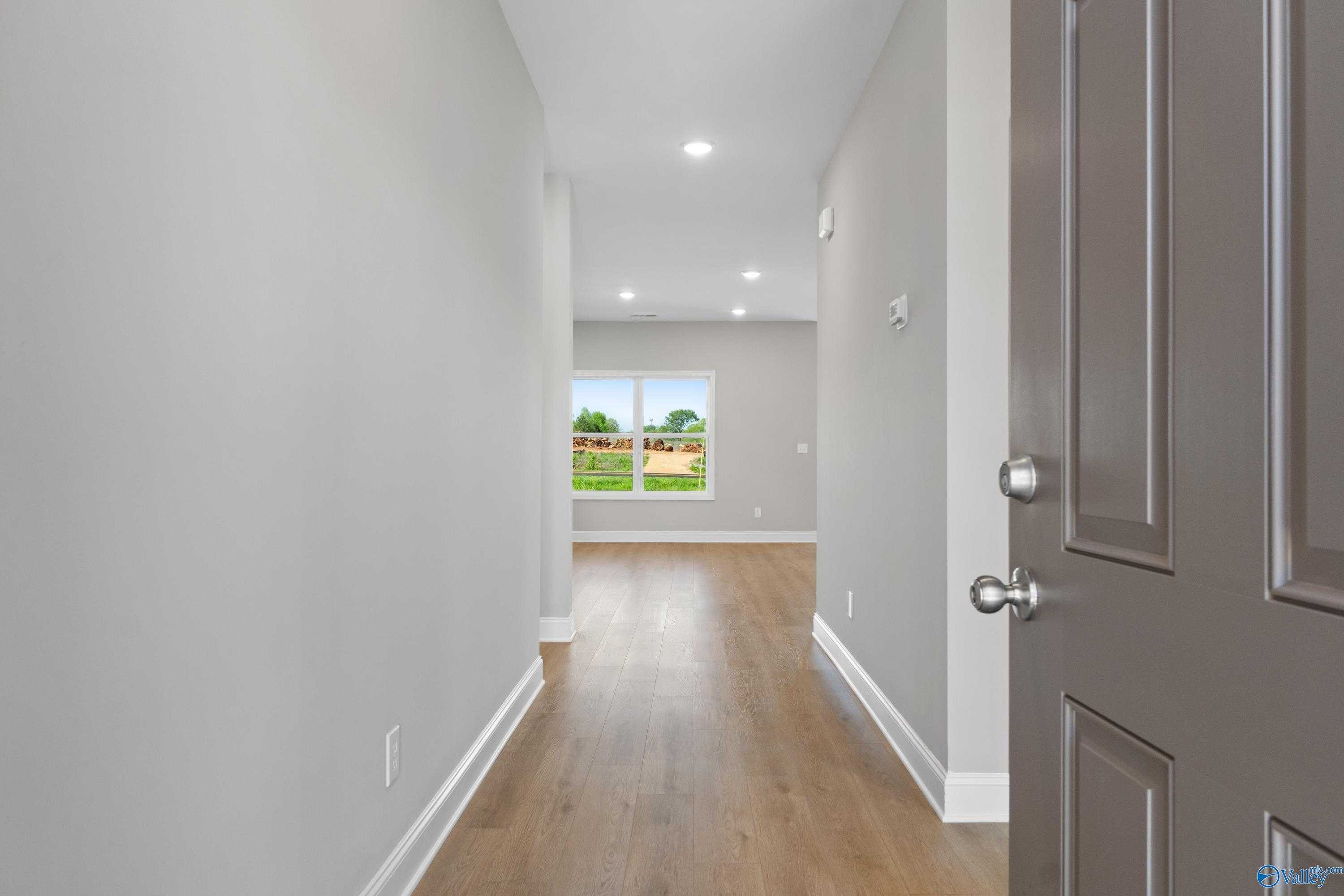 Bright hallway with light oak floors, gray walls, and window view in The Asheville C 3-bedroom home, Athens, Alabama