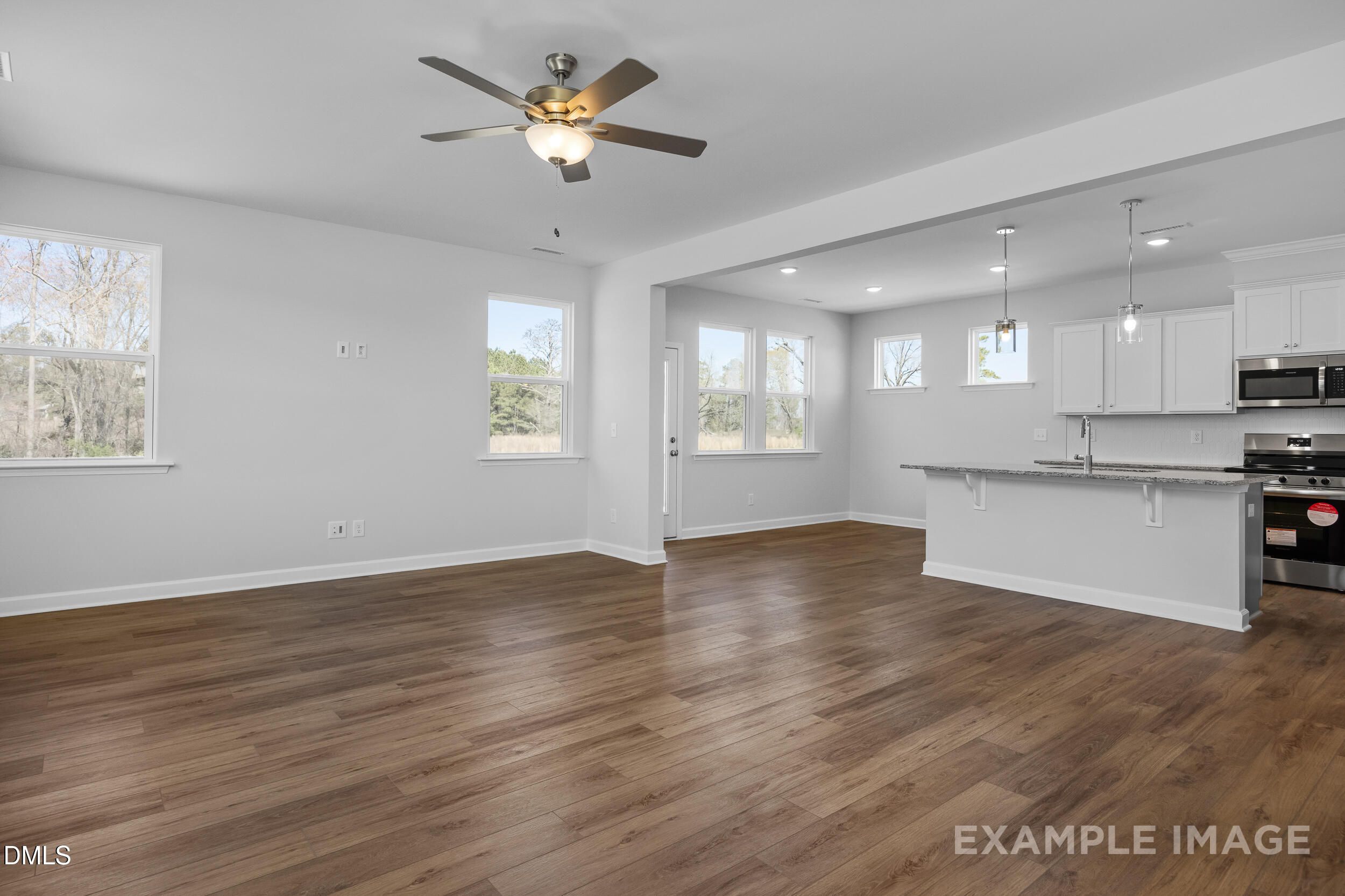 Open-concept living room and kitchen with wood flooring in The Gavin A floor plan at Gregory Village, Lillington, NC.