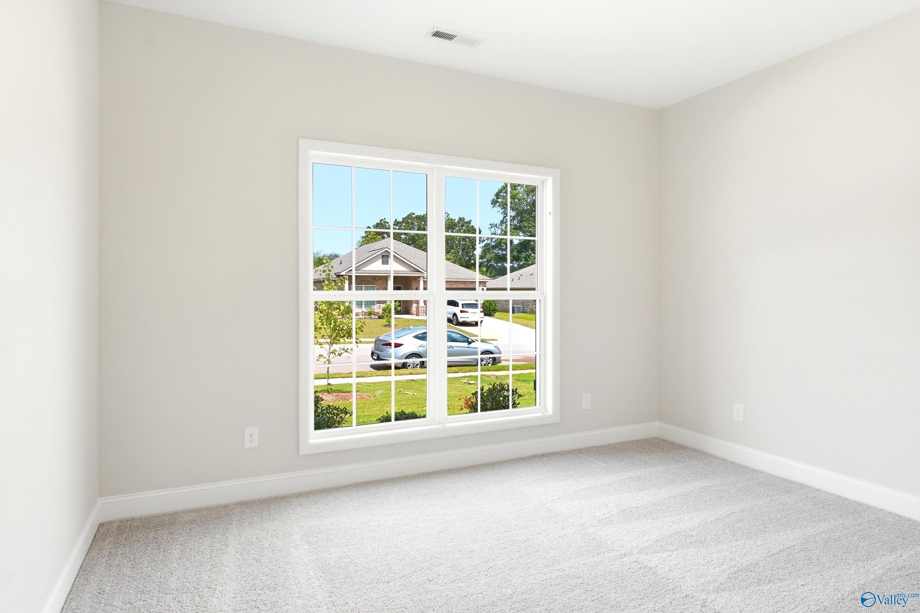 Bright bedroom with neutral carpet and large window in The Daphne C floor plan at Flint Meadows, New Market, AL.