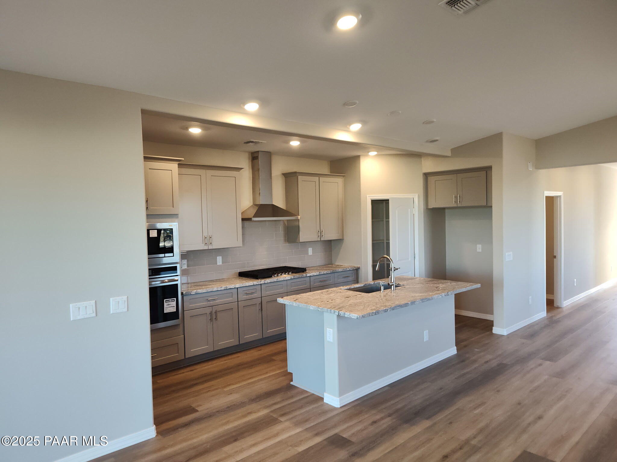 Modern open-concept kitchen with granite island, stainless steel appliances, and shaker cabinets in Davidson Homes The Frontier A, Prescott Valley, AZ