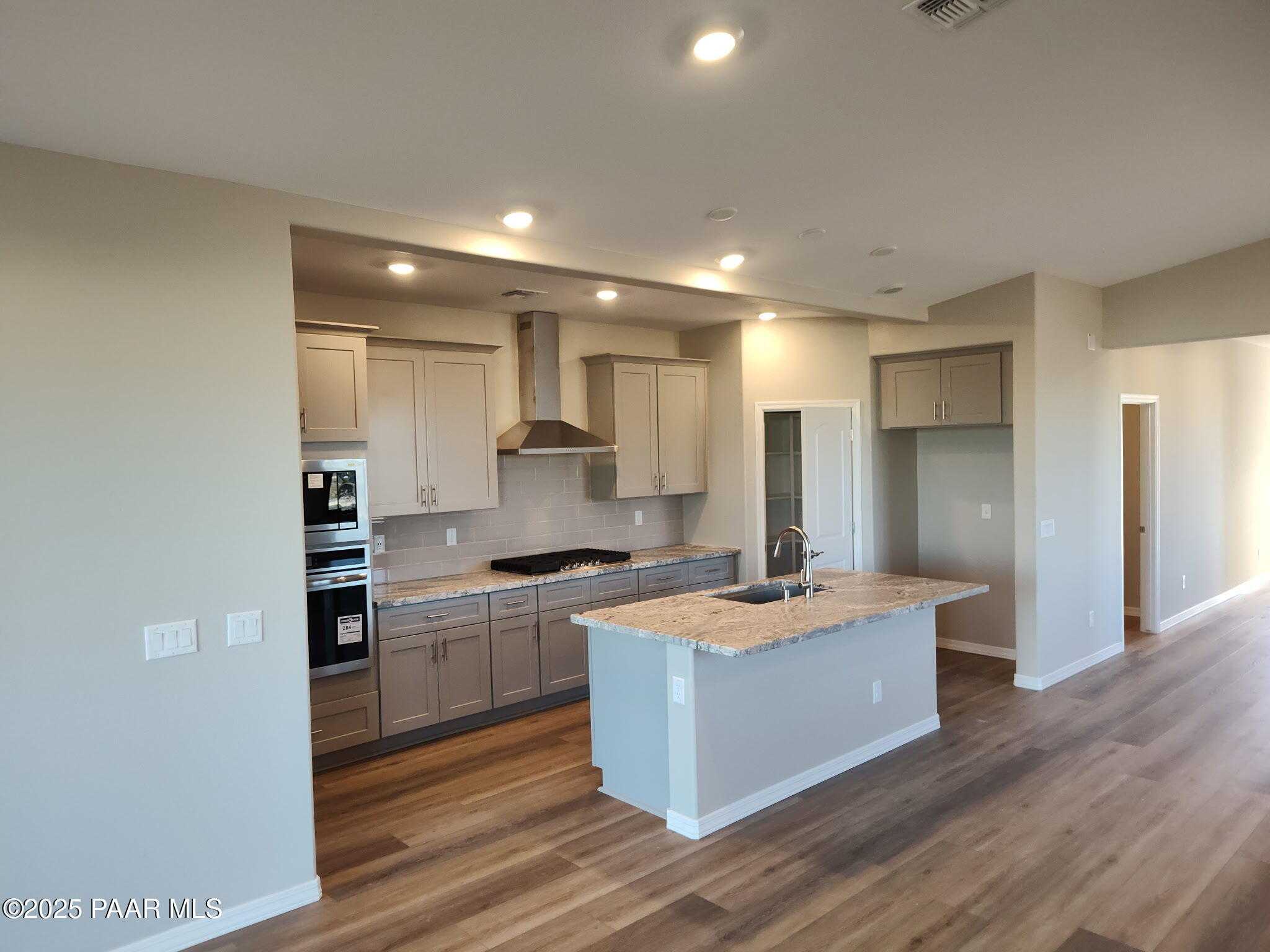 Modern open-concept kitchen with granite island, stainless steel appliances, and shaker cabinets in Davidson Homes The Frontier A, Prescott Valley, AZ