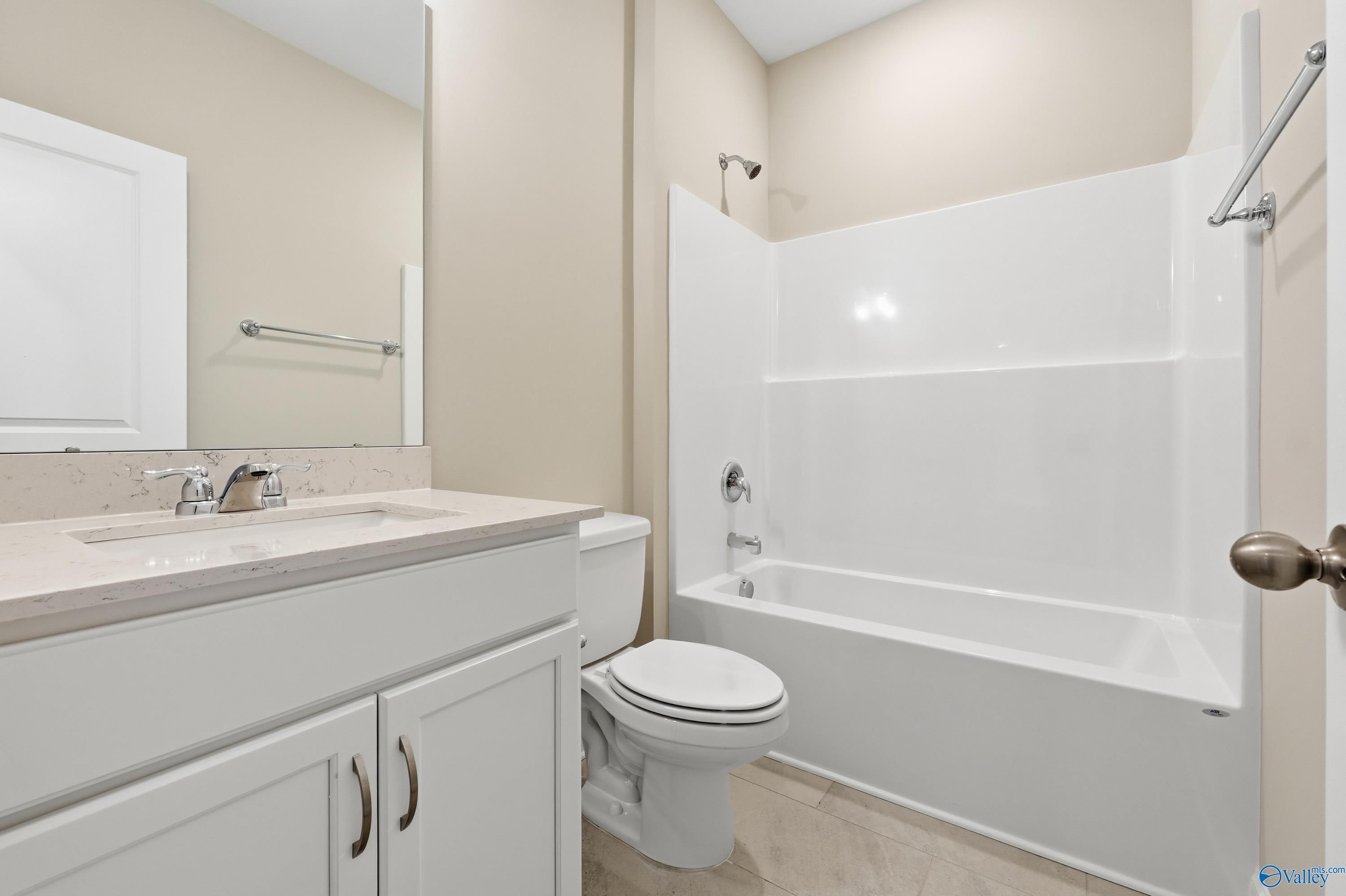 Guest bathroom with white tub-shower combo, quartz vanity sink, and neutral walls in Davidson Homes The Lanier, Pikes Ridge Meridianville AL