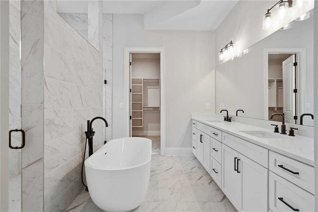 Luxurious master bath with freestanding soaking tub, double vanity, and marble accents in Davidson Homes The Seaside B, Woodstock, GA