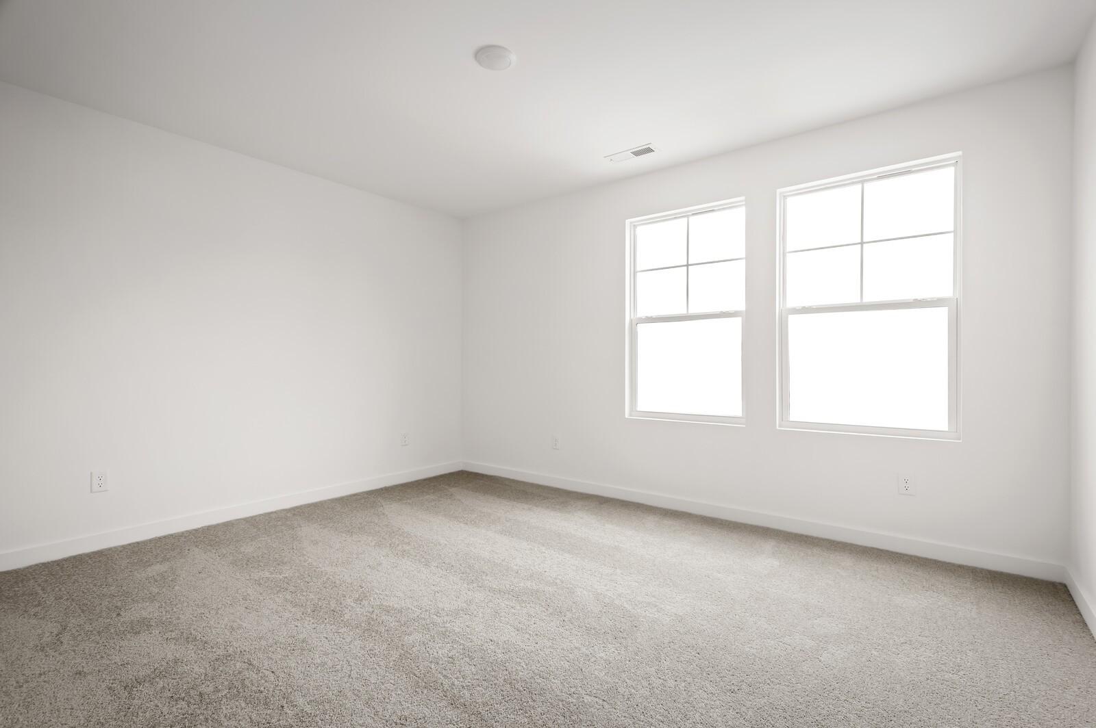 Bright, carpeted bedroom with large windows in The Logan C floor plan at Calista Farms in White House, Tennessee.
