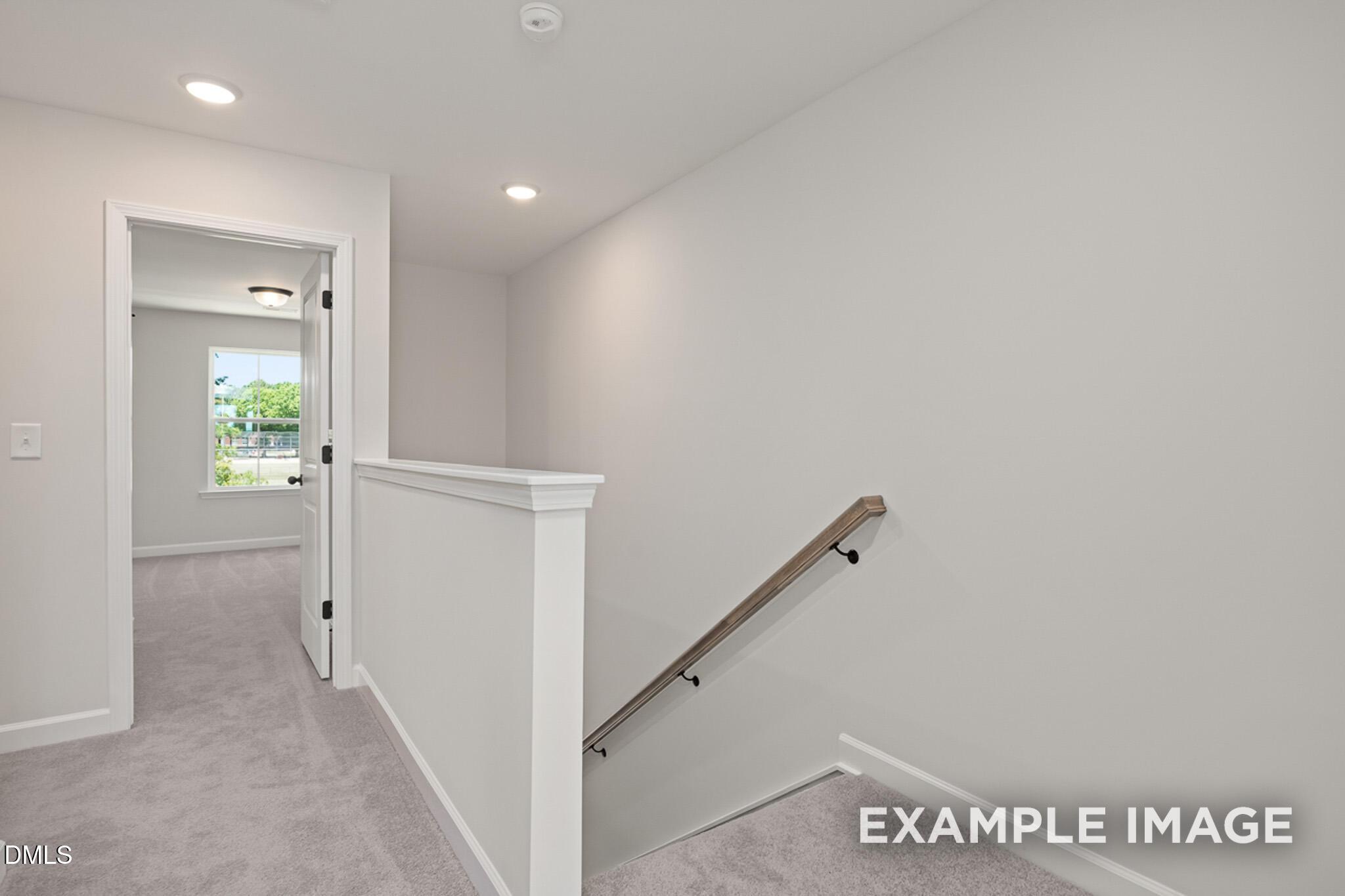 Bright, carpeted landing with staircase and open doorway in The Mitchell floor plan by Davidson Homes, Knightdale, NC.