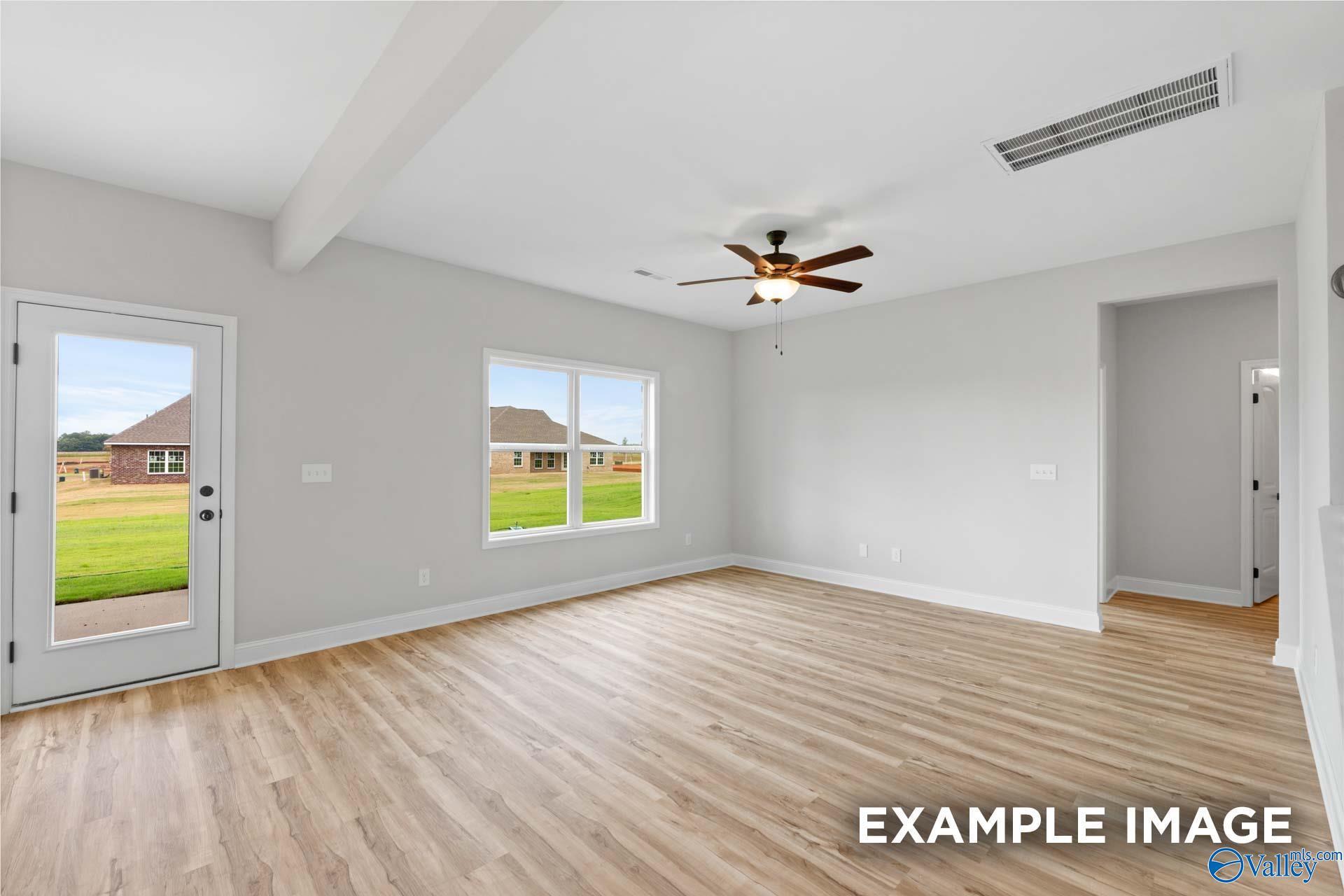 Spacious living room with wood-look flooring and ceiling fan in The Shelby B floor plan at Jaguar Hills, Huntsville, AL.