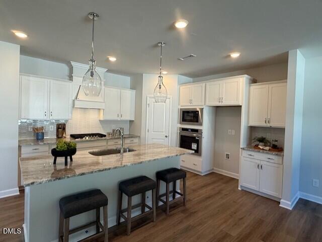 Modern white kitchen with granite island, farmhouse sink, stainless double oven, and pendant lights in The Preston C home, Lillington, NC