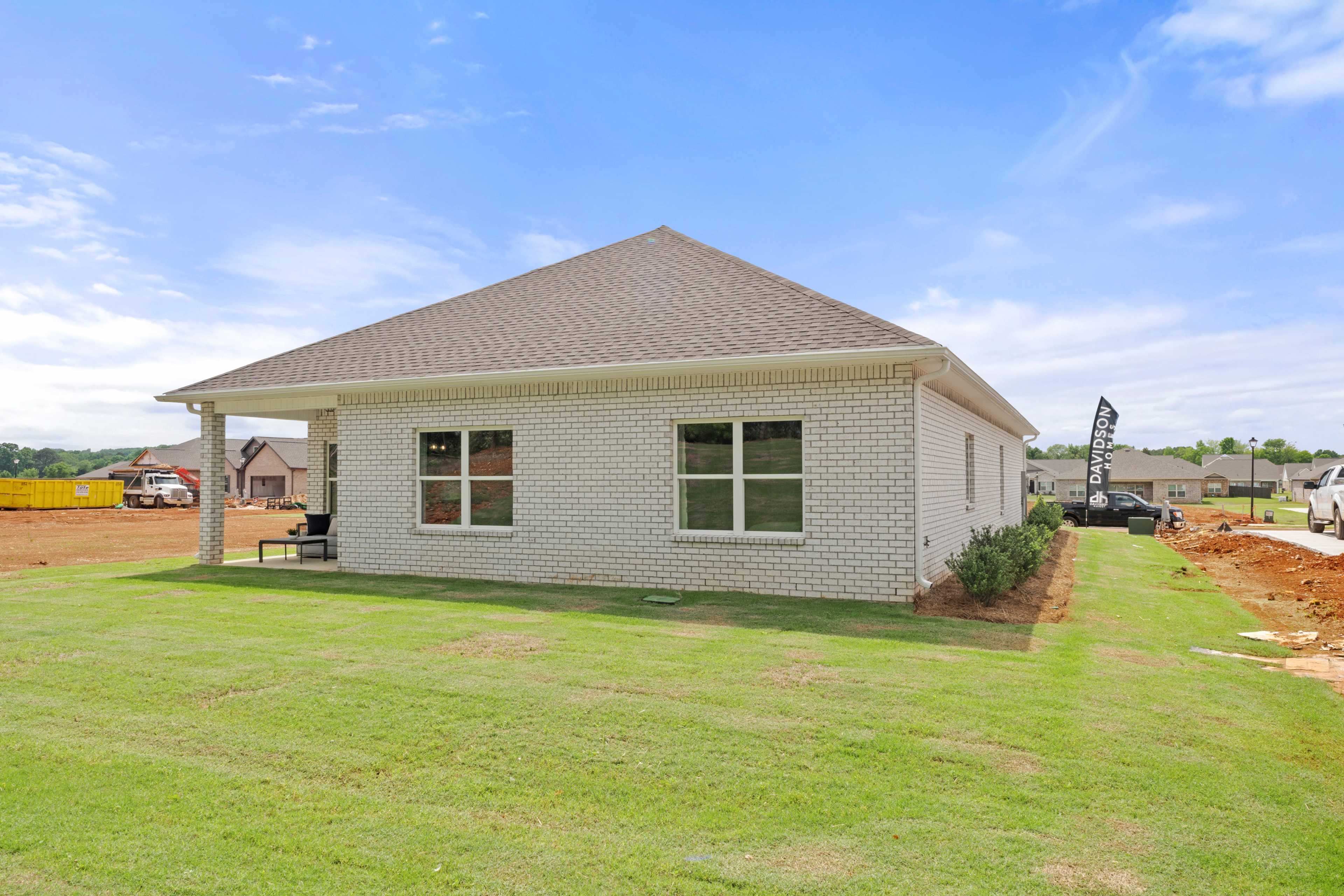 White brick ranch home exterior at Ivy Hills in Toney, Alabama with covered porch, gabled roof and lush green lawn