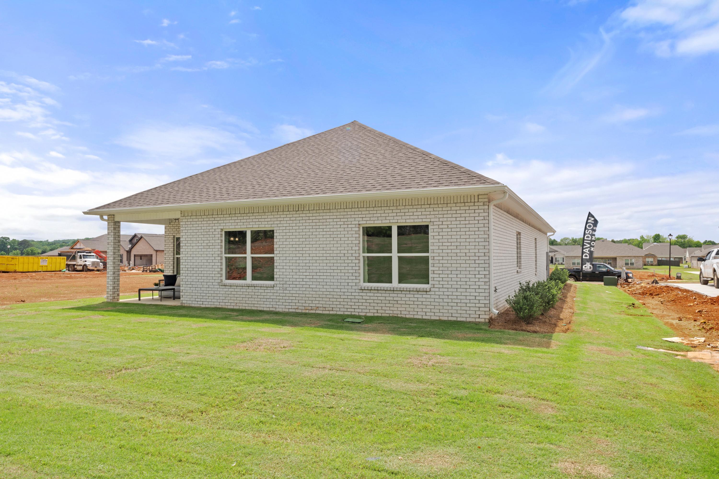 White brick ranch home exterior at Ivy Hills in Toney, Alabama with covered porch, gabled roof and lush green lawn