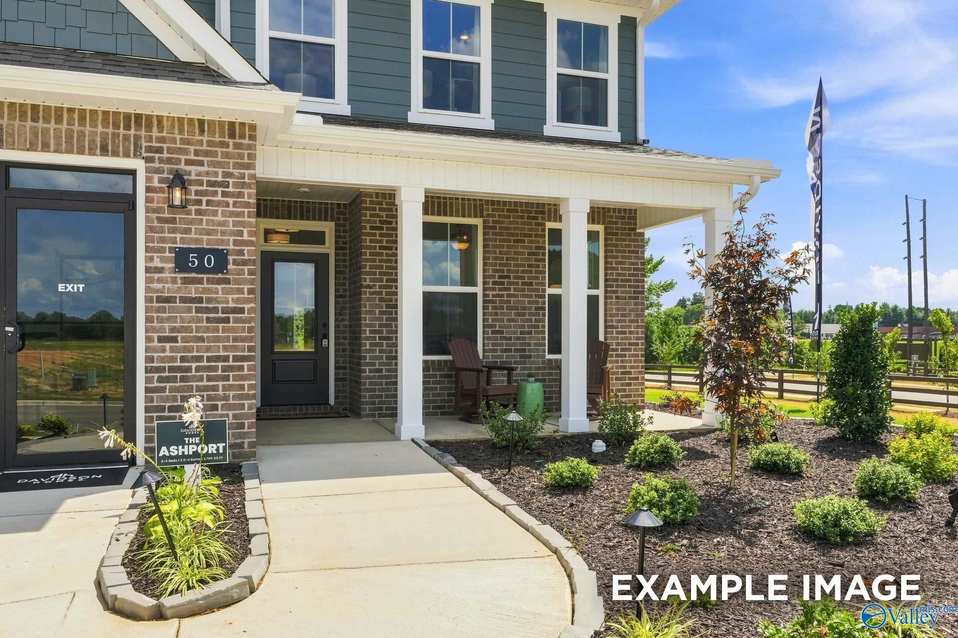 Front porch entrance with brick exterior and landscaped yard at The Ashport L model home by Davidson Homes in Berry Cove, New Market, Alabama