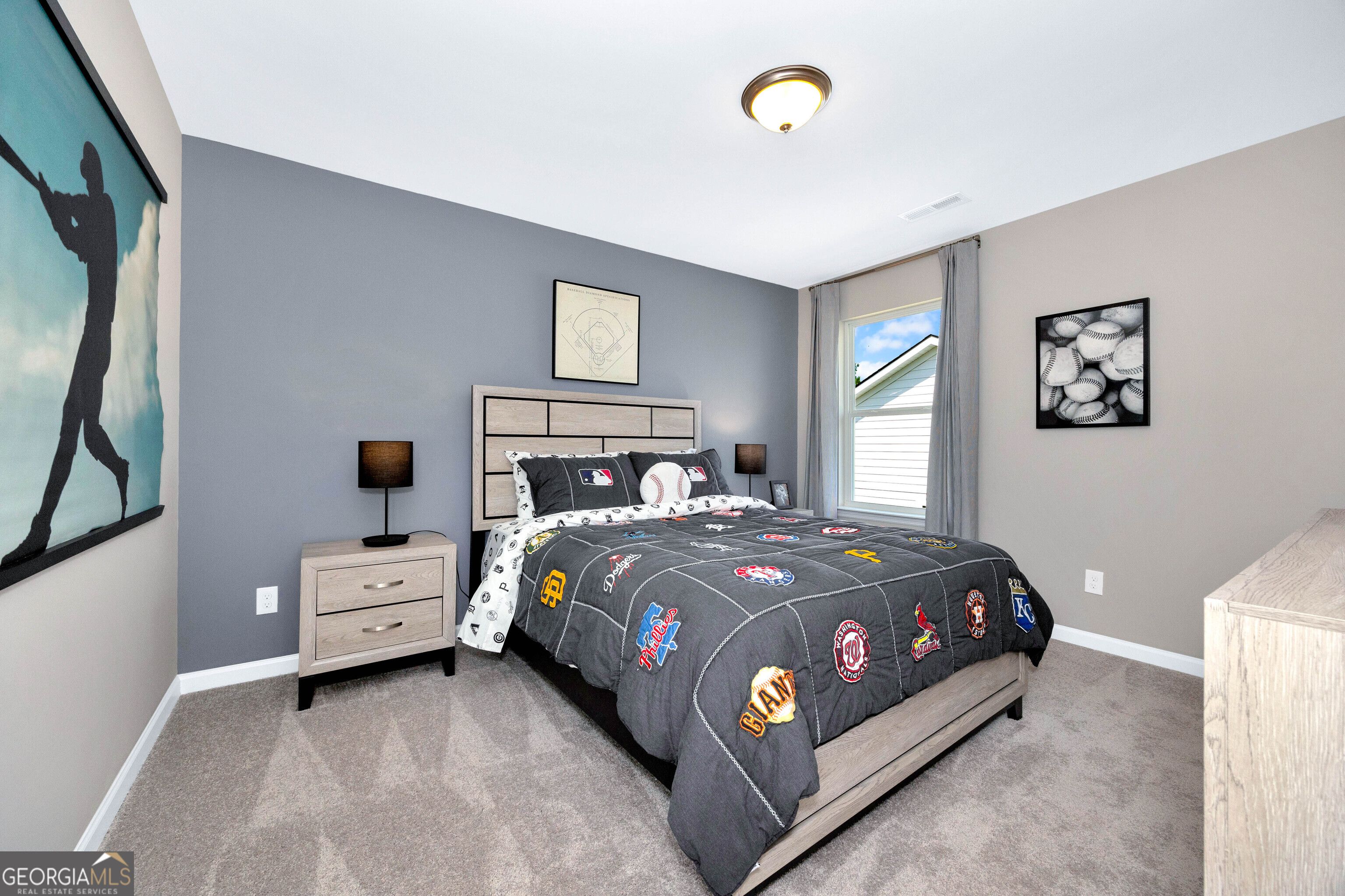 Sports-themed bedroom with baseball artwork, gray bedding on queen bed, nightstands in Evermore Homes The Stella, Perry, Georgia