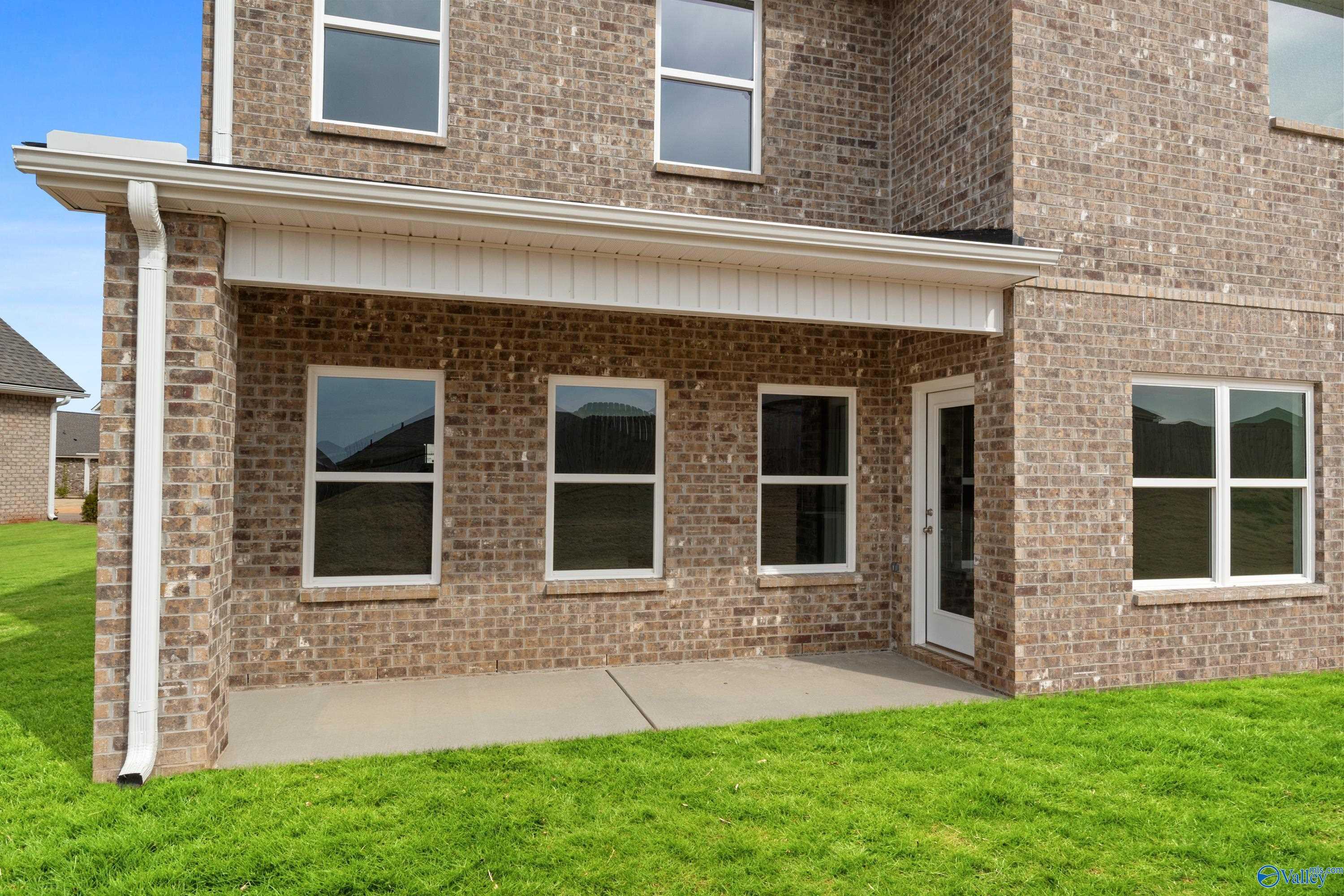 Two-story brick home with covered side porch, large windows, and lush green lawn in Walker's Hill, Meridianville, Alabama
