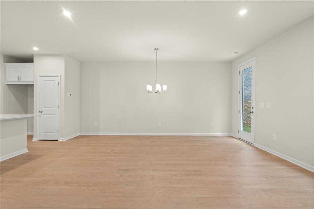 Spacious open living room with hardwood floors, chandelier, and sliding glass doors in Davidson Homes The Cary A, Kennesaw, GA