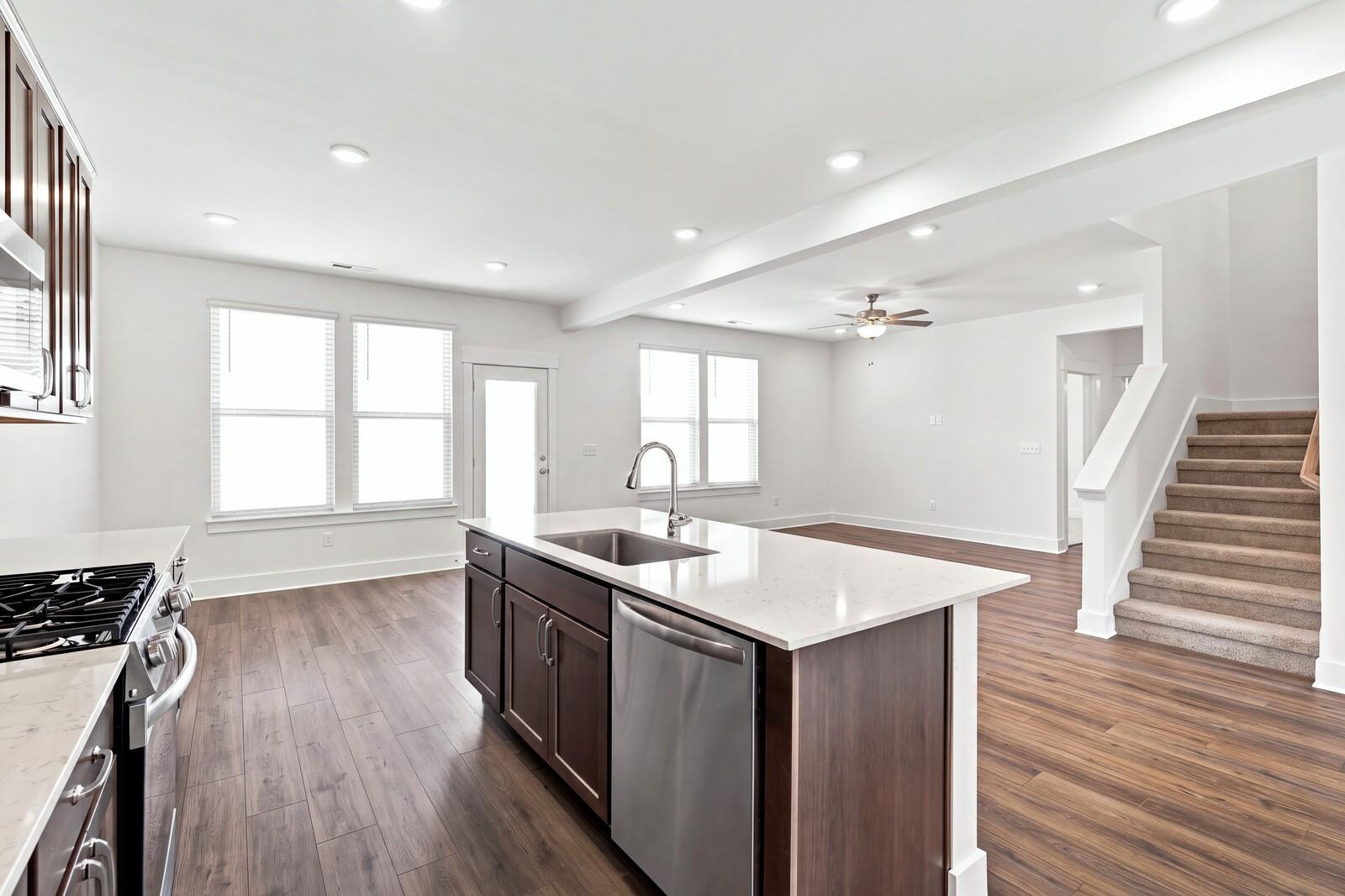 Open-concept kitchen with island sink and dark wood cabinets flowing into great room in Davidson Homes Willow C, Gallatin TN