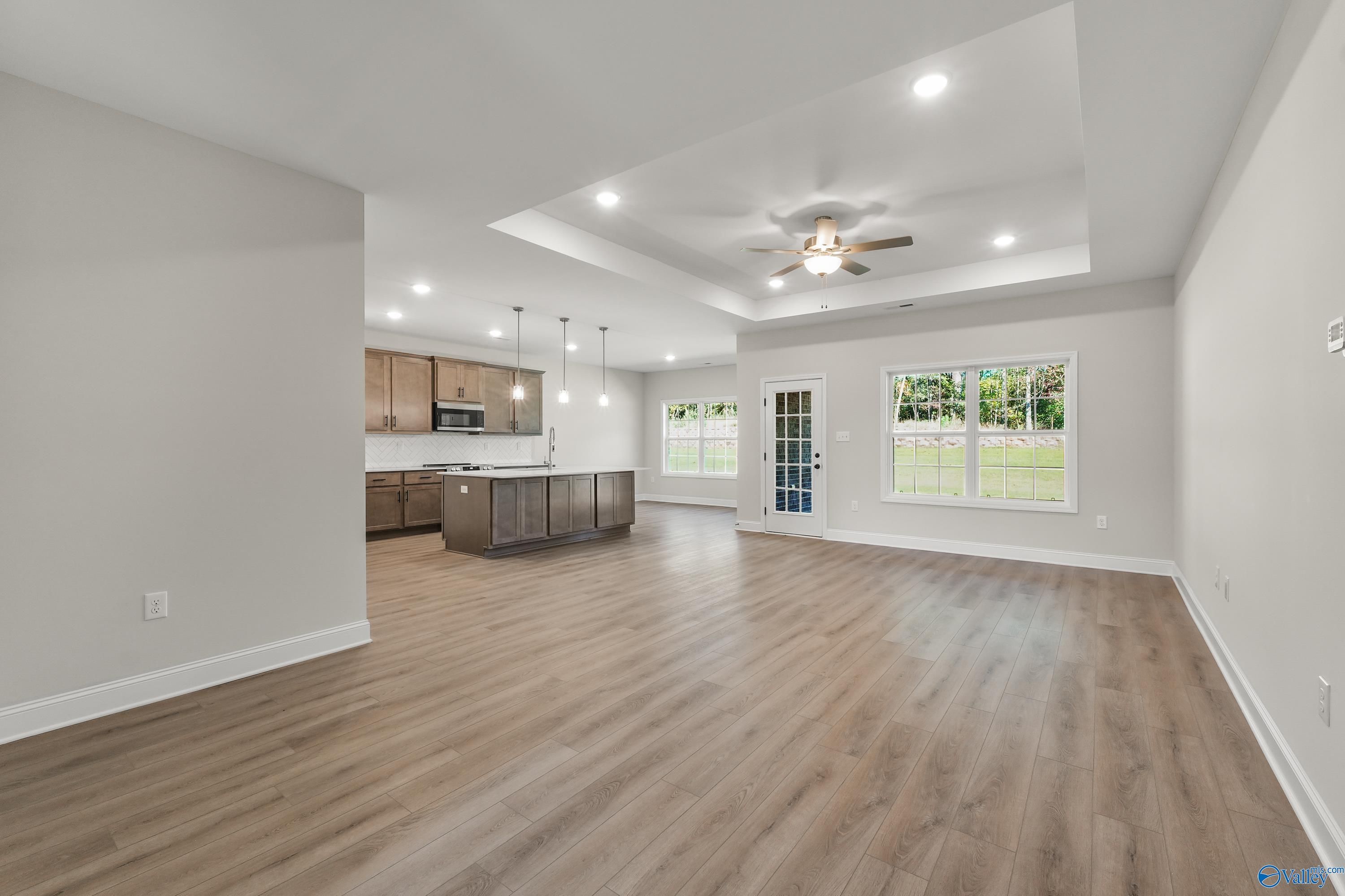 Open-concept kitchen and living area with island, hardwood floors, ceiling fan, and French doors to backyard in The Montgomery C, Decatur, AL
