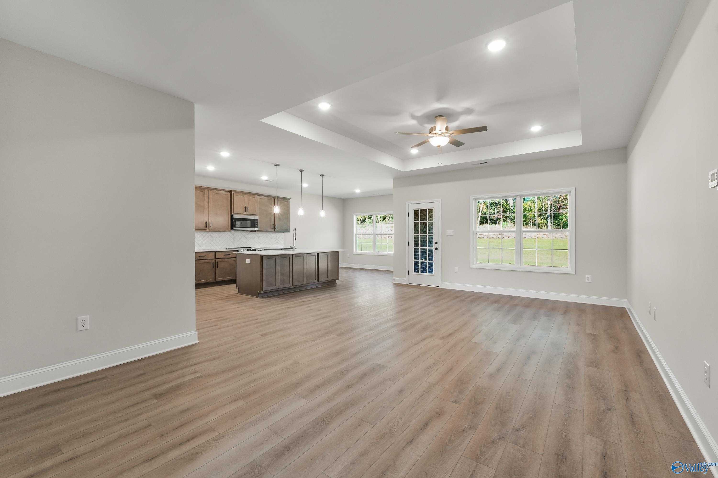 Open-concept kitchen and living area with island, hardwood floors, ceiling fan, and French doors to backyard in The Montgomery C, Decatur, AL