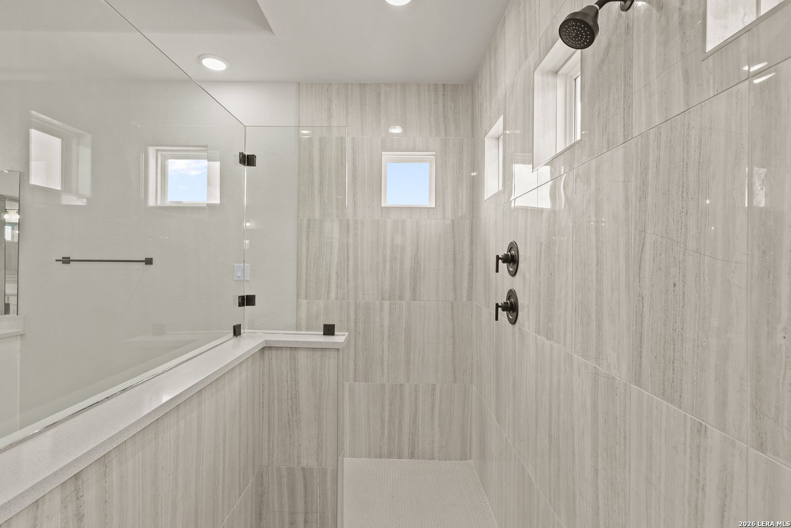 Modern walk-in shower with floor-to-ceiling tile in The Summerlin B floor plan by Davidson Homes in Castroville, Texas.
