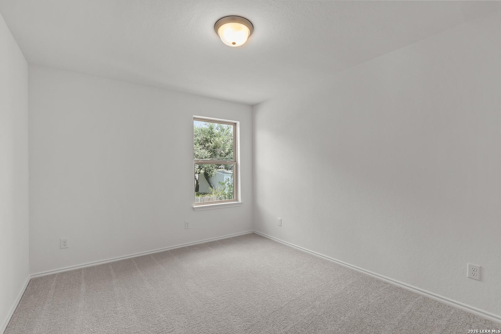 Bright bedroom with neutral carpet and window view in The Gillian C floor plan by Davidson Homes, San Antonio, Texas.
