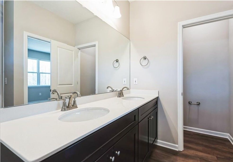 Modern master bathroom double vanity with white quartz countertop, dark cabinets, mirrors in Evermore Homes The Aurora A, Cusseta, Alabama