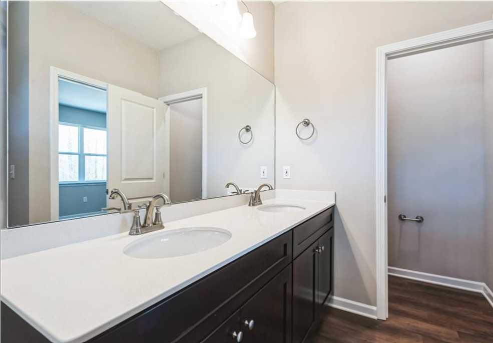 Modern master bathroom double vanity with white quartz countertop, dark cabinets, mirrors in Evermore Homes The Aurora A, Cusseta, Alabama