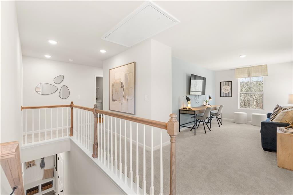 Spacious upstairs loft with wooden railing, modern desk, navy couch, and abstract art in Davidson Homes The Burton C, Canton GA