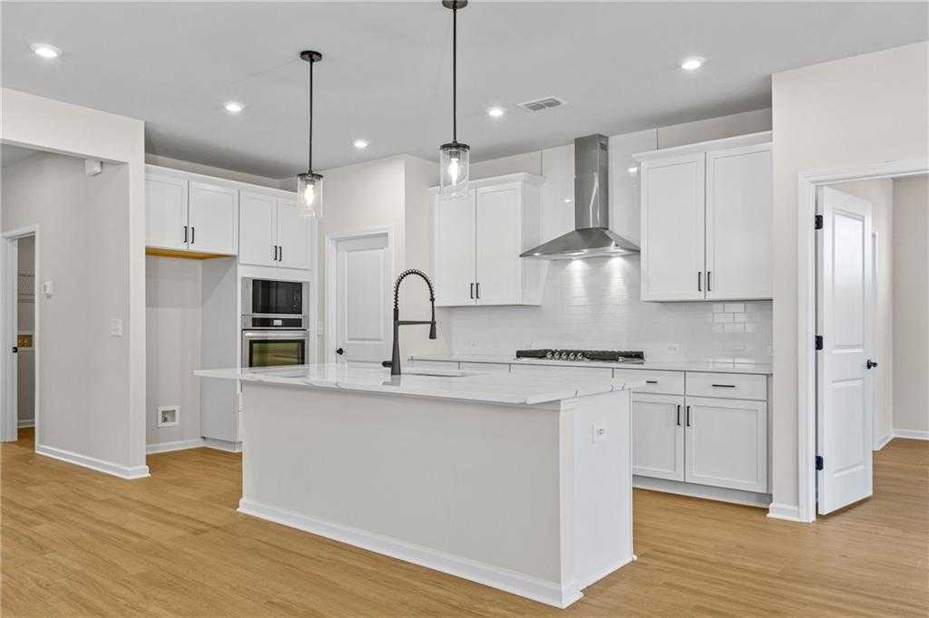 Bright modern kitchen with white shaker cabinets, quartz island, stainless appliances in The Edison A home, Loganville, GA