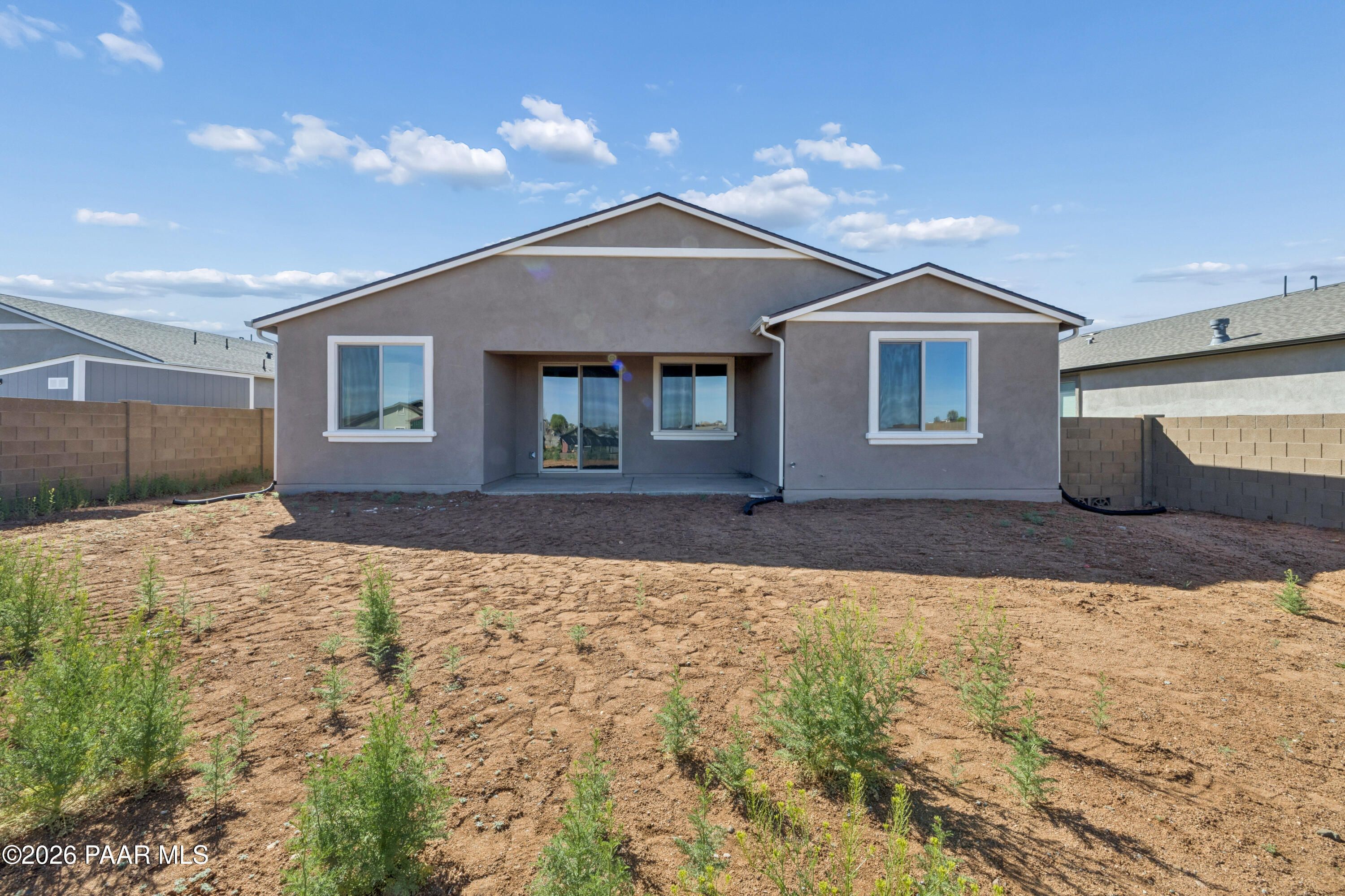 Back view of The Harmony A single-story home featuring covered patio, large windows, and desert yard in North Ridge at Pronghorn Ranch, Prescott Valley, Arizona