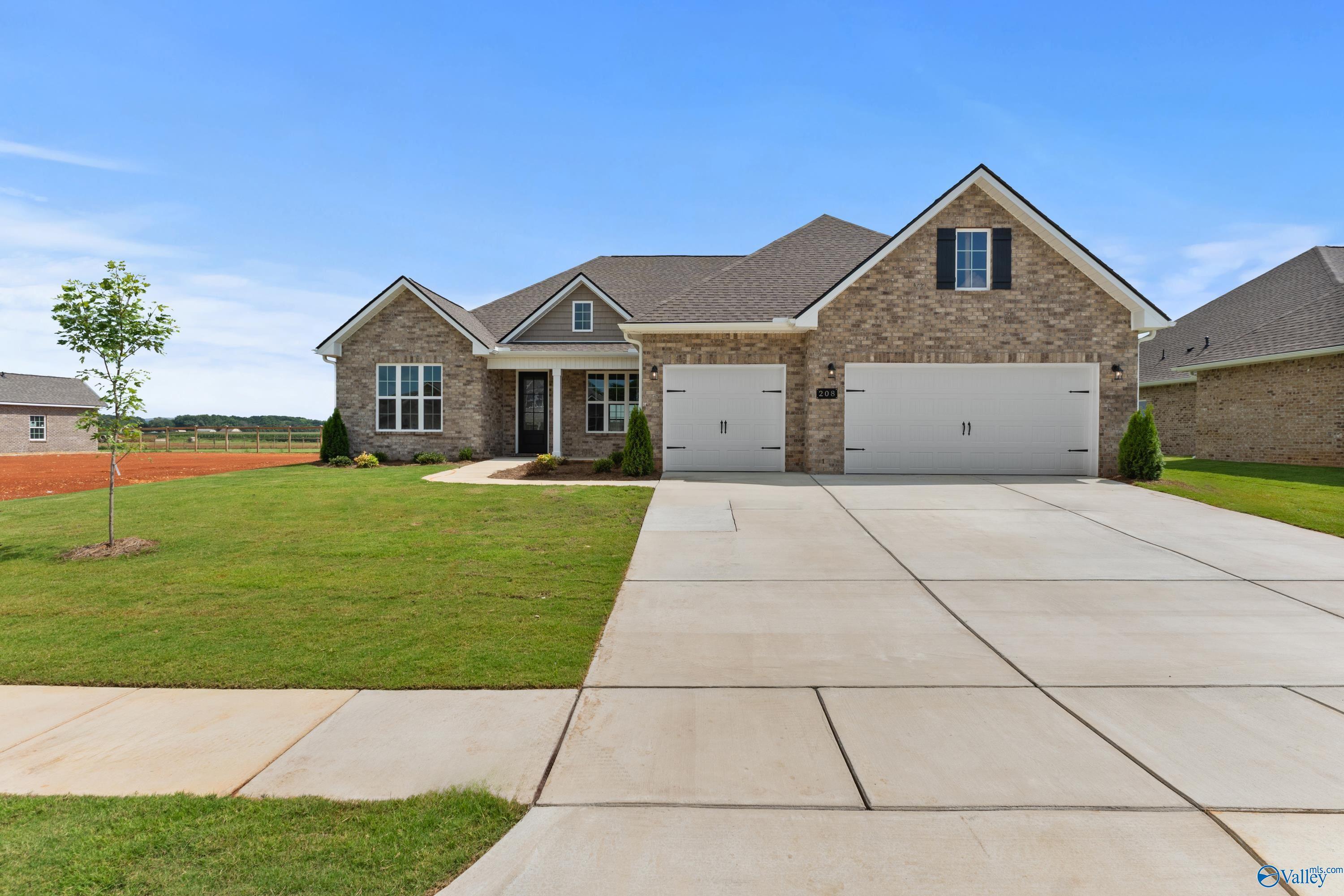 Brick 1-story home with 2-car garage, front porch, driveway, and manicured lawn in Kendall Farms, Toney, Alabama by Davidson Homes Finleigh