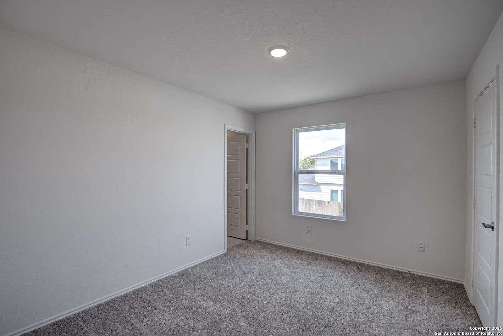 Bright secondary bedroom with gray carpet, white walls, double doors, and window in Davidson Homes The Douglas B, Seguin, Texas