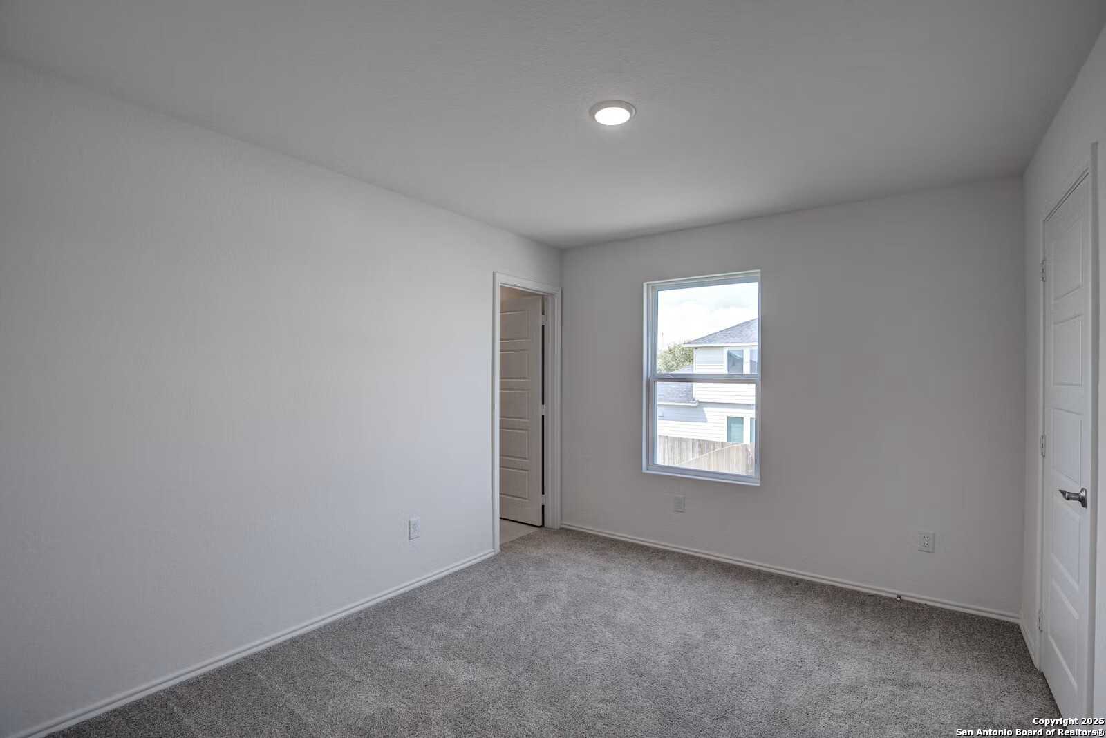 Bright secondary bedroom with gray carpet, white walls, double doors, and window in Davidson Homes The Douglas B, Seguin, Texas