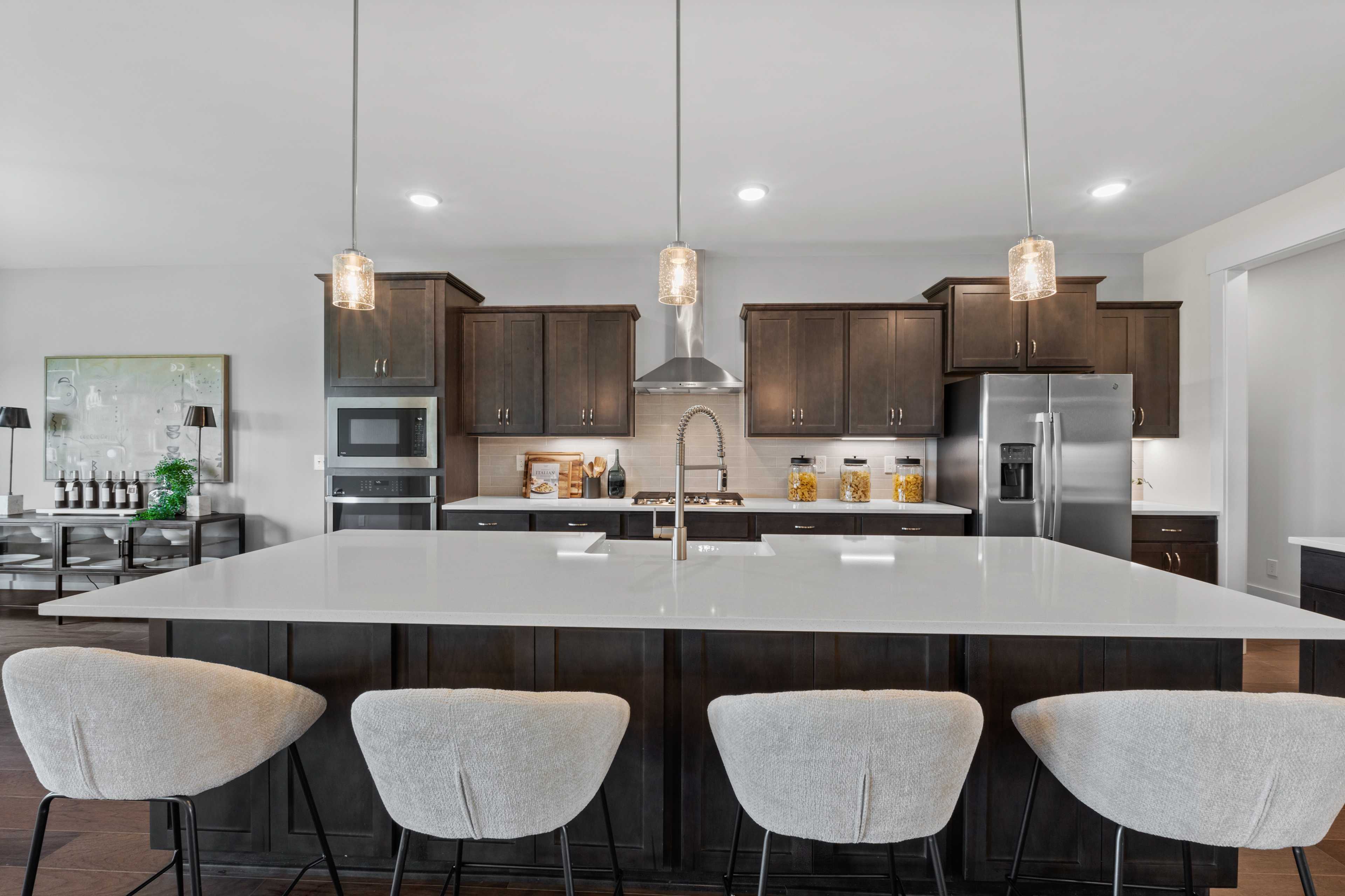 Modern kitchen at Creekside in Harvest Alabama with white quartz island, dark wood cabinets, stainless appliances, and pendant lights