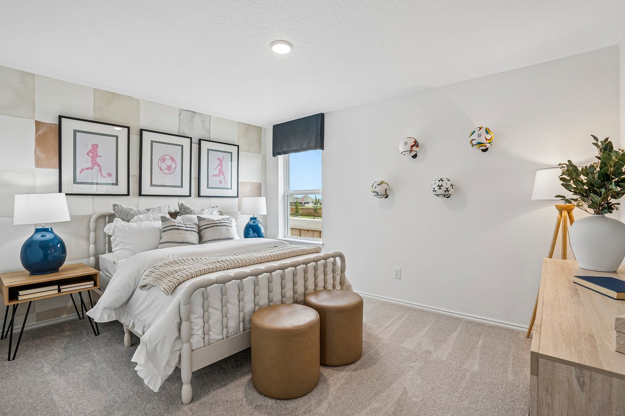 Spacious bedroom at Morgan Meadows in San Antonio with soccer-themed decor, spindle bed frame, and modern furniture.