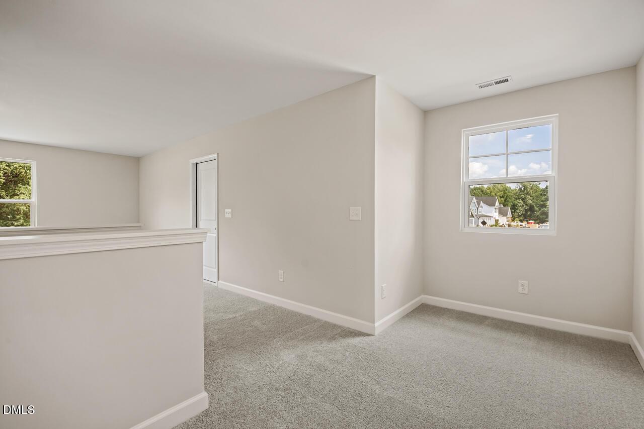 Bright carpeted loft area in The Ash C floor plan at Woodland Crossing in Zebulon, North Carolina.