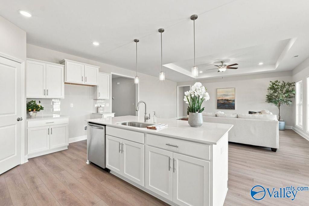 White kitchen island with sink and pendant lights overlooking great room in Davidson Homes The Harrison, Cain Park, Hartselle, Alabama