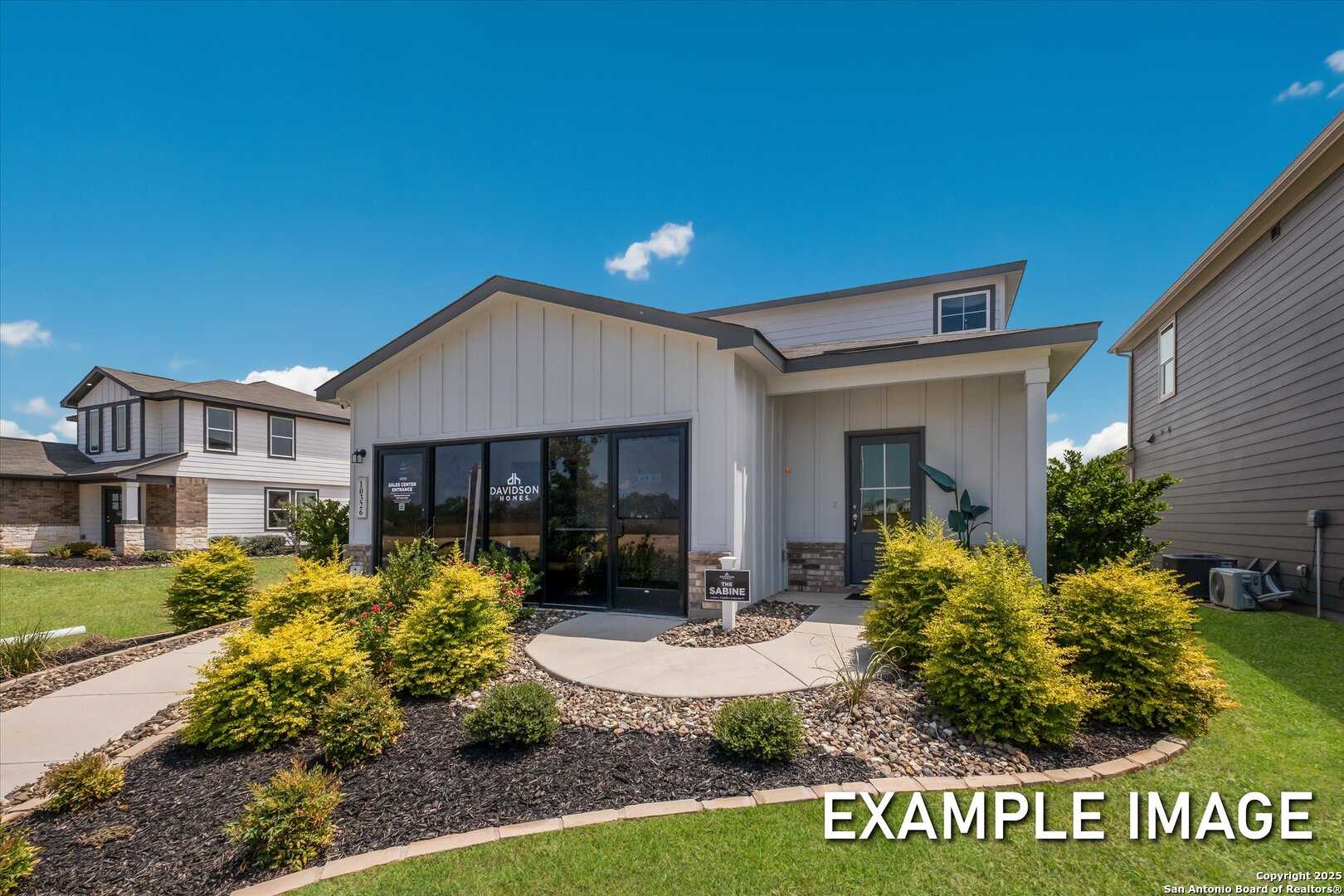 Modern two-story Sabine C home exterior featuring white board-and-batten siding, large front windows, stone accents, and landscaped yard in Agave, San Antonio by Davidson Homes